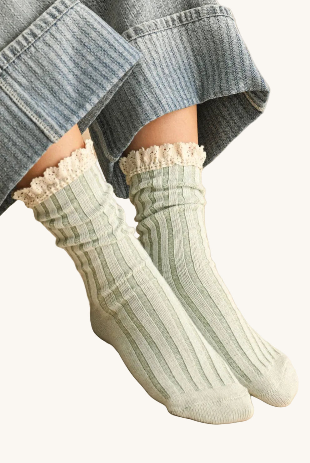 Person wearing green ribbed socks with lace trim on a stone floor.