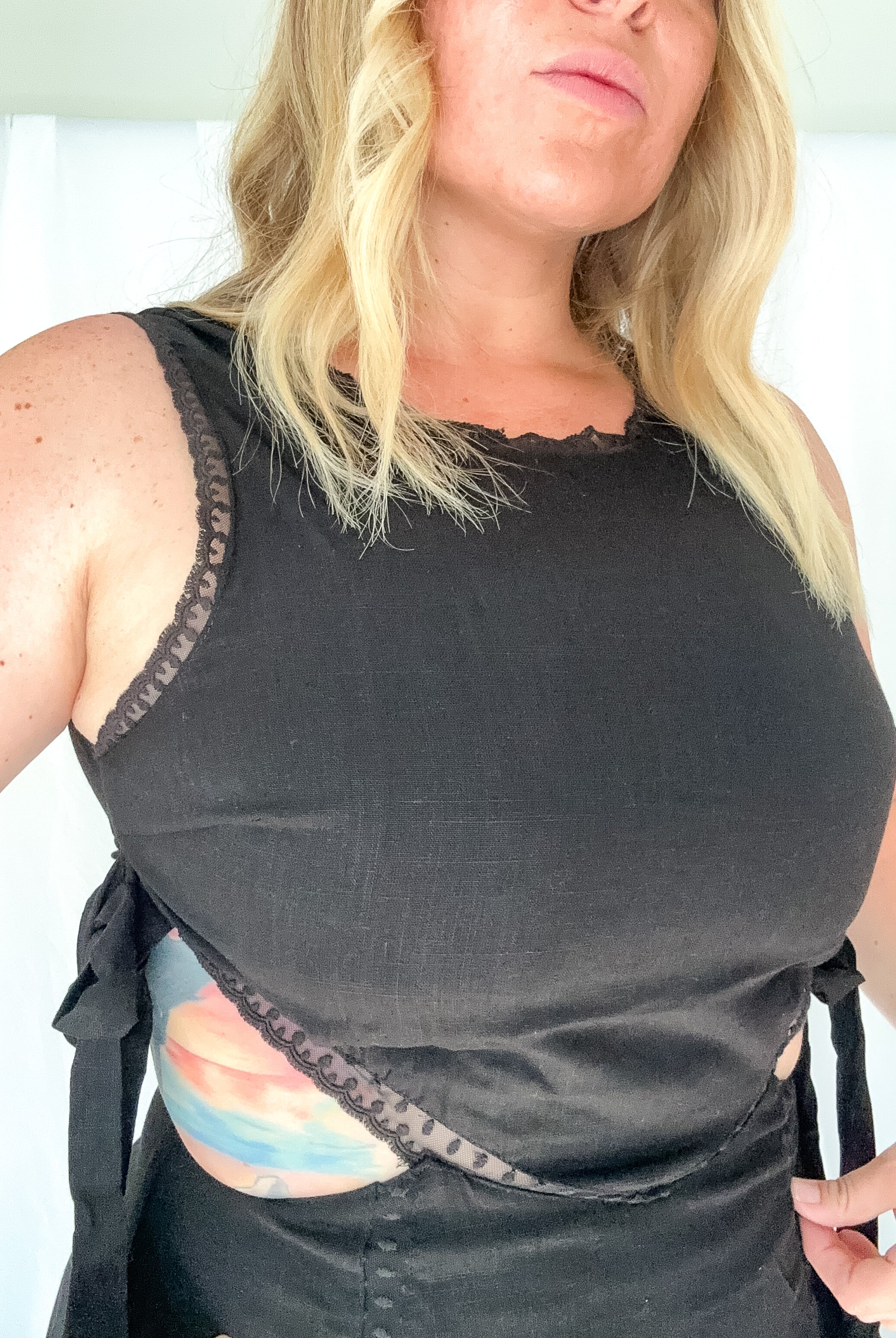 Woman wearing a black sleeveless top with lace trim on a white background