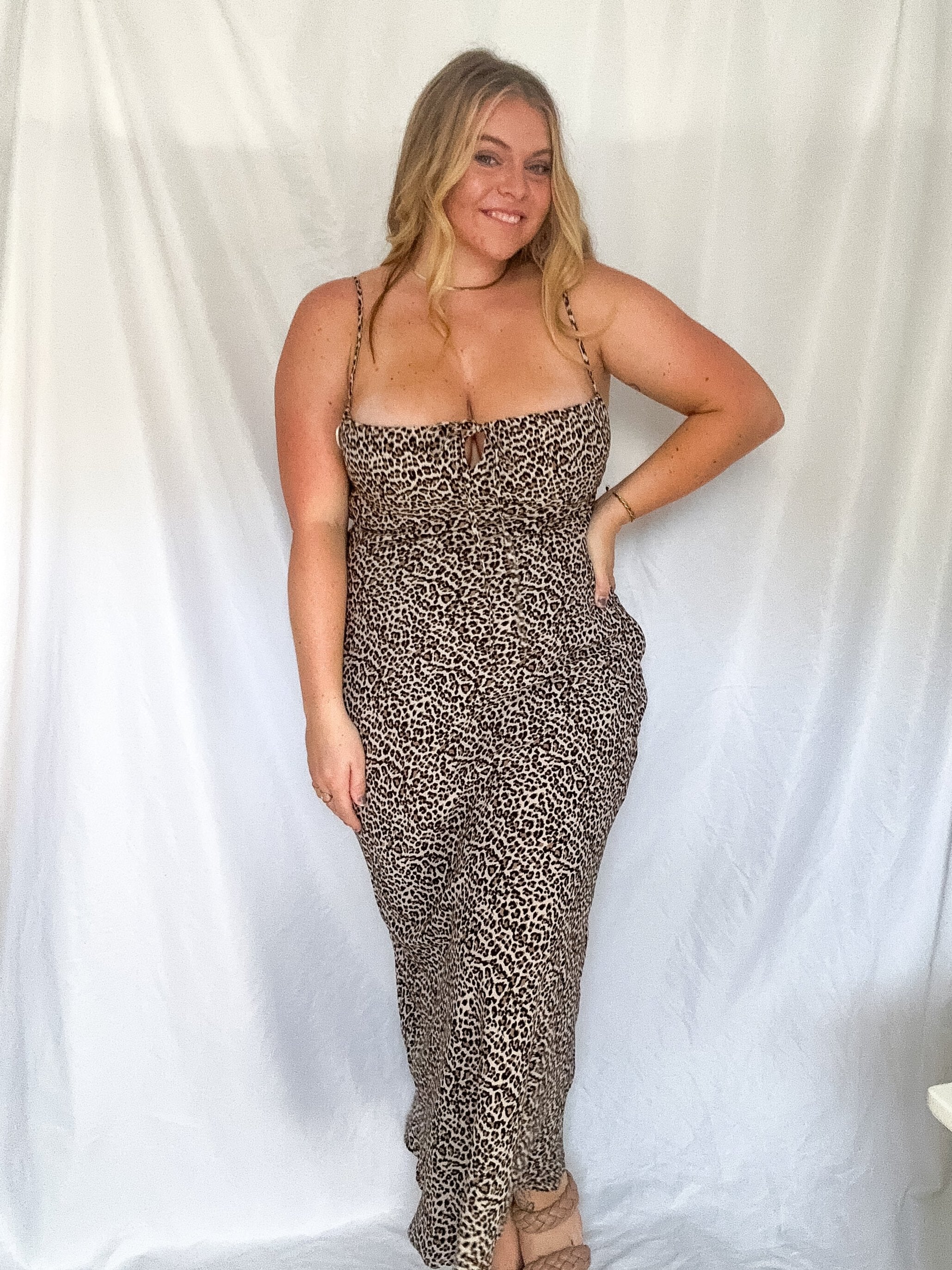 A model wearing a leopard print maxi dress with a shirred neckline, keyhole cut out with tie detail, and adjustable straps, standing against a white background.