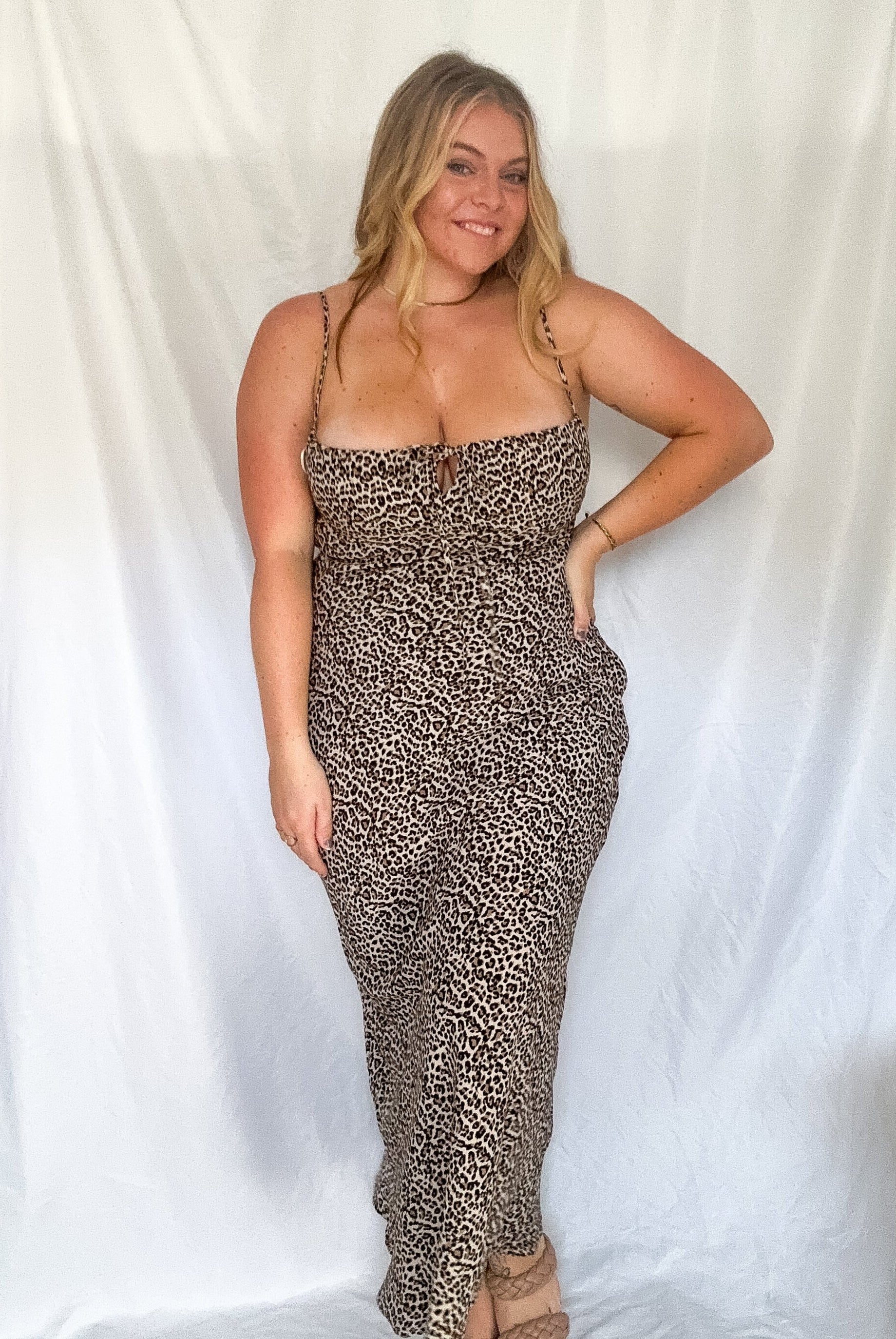 A woman wearing a leopard print maxi dress with a shirred neckline and adjustable straps.