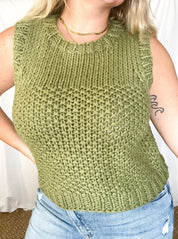 A model wearing a green sleeveless sweater top with a knit pattern.