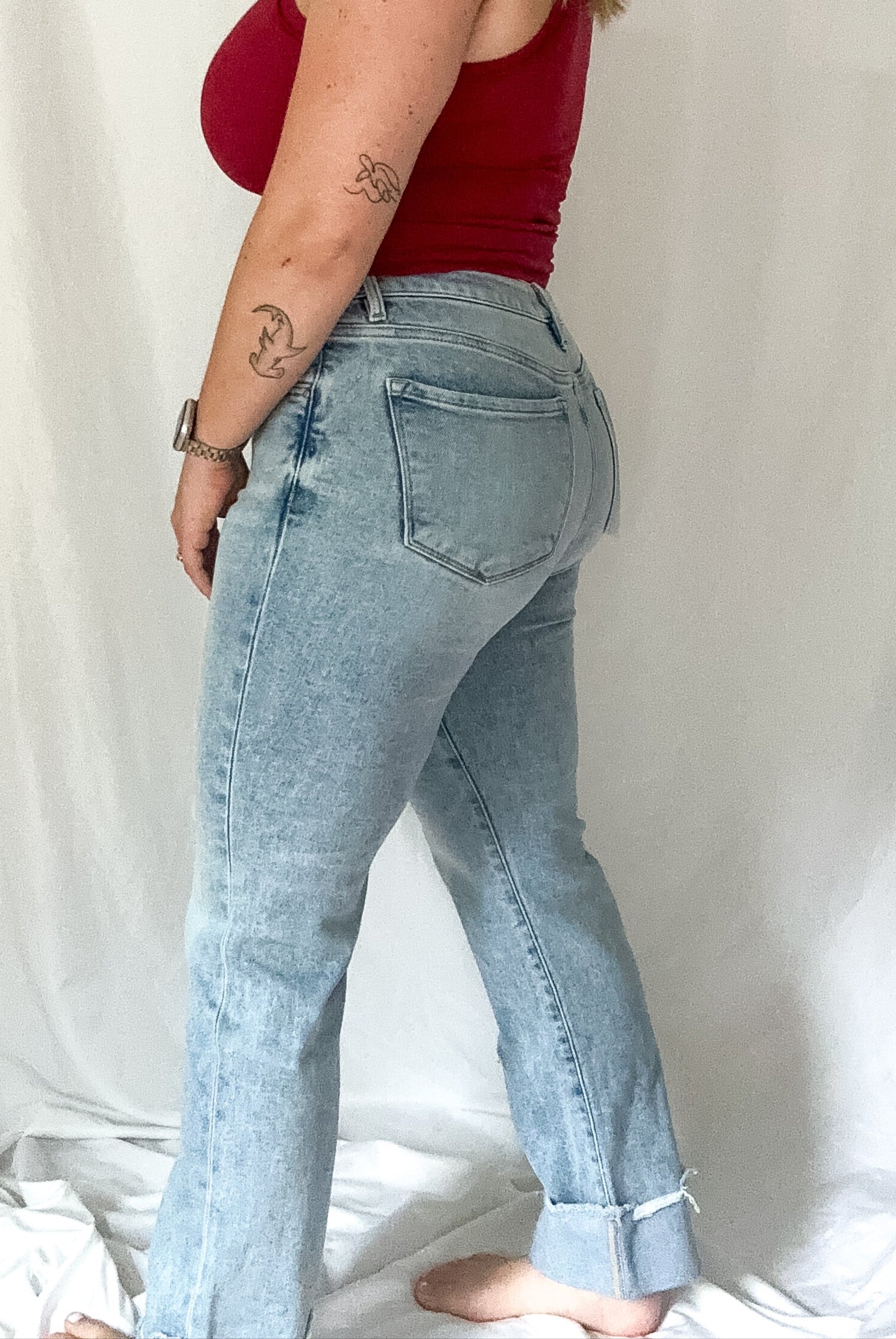 Woman wearing a red top and light blue jeans against a white background
