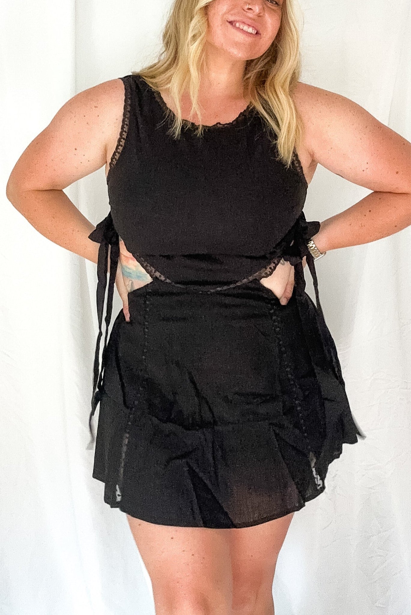 Woman wearing a black outfit with sheer details against a white background