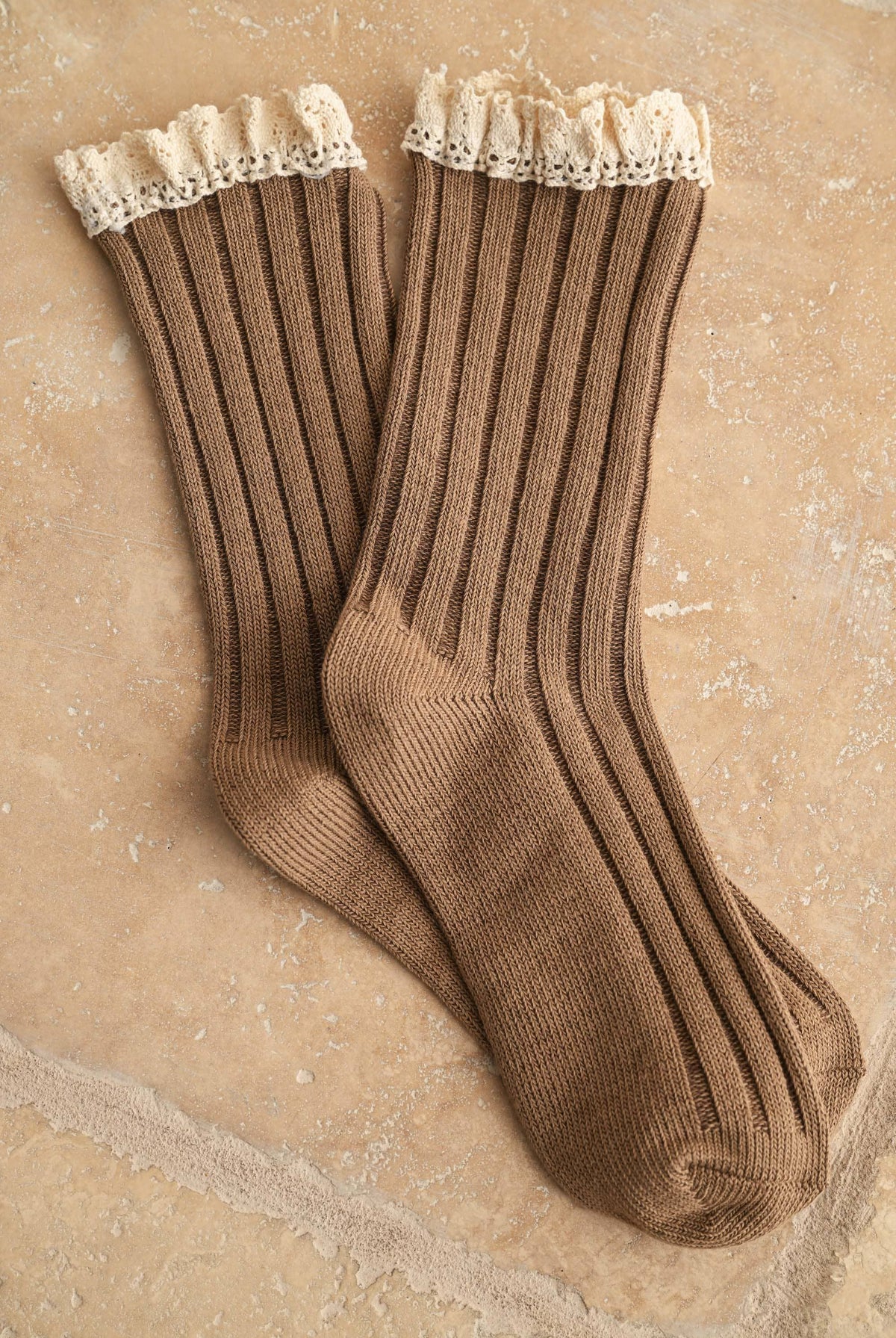 Brown ribbed socks with delicate crochet trim on a textured surface.