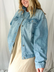 Person wearing a light blue denim jacket against a plain background