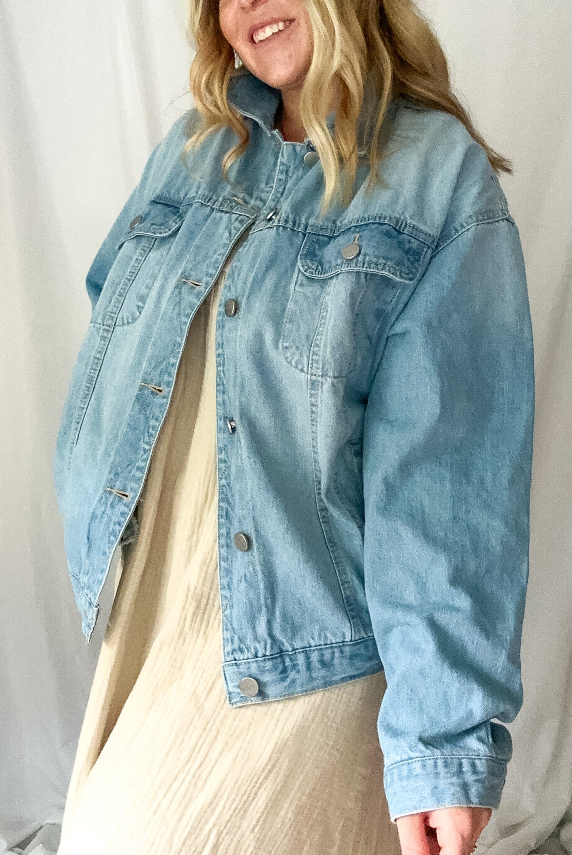 Person wearing a light blue denim jacket against a plain background