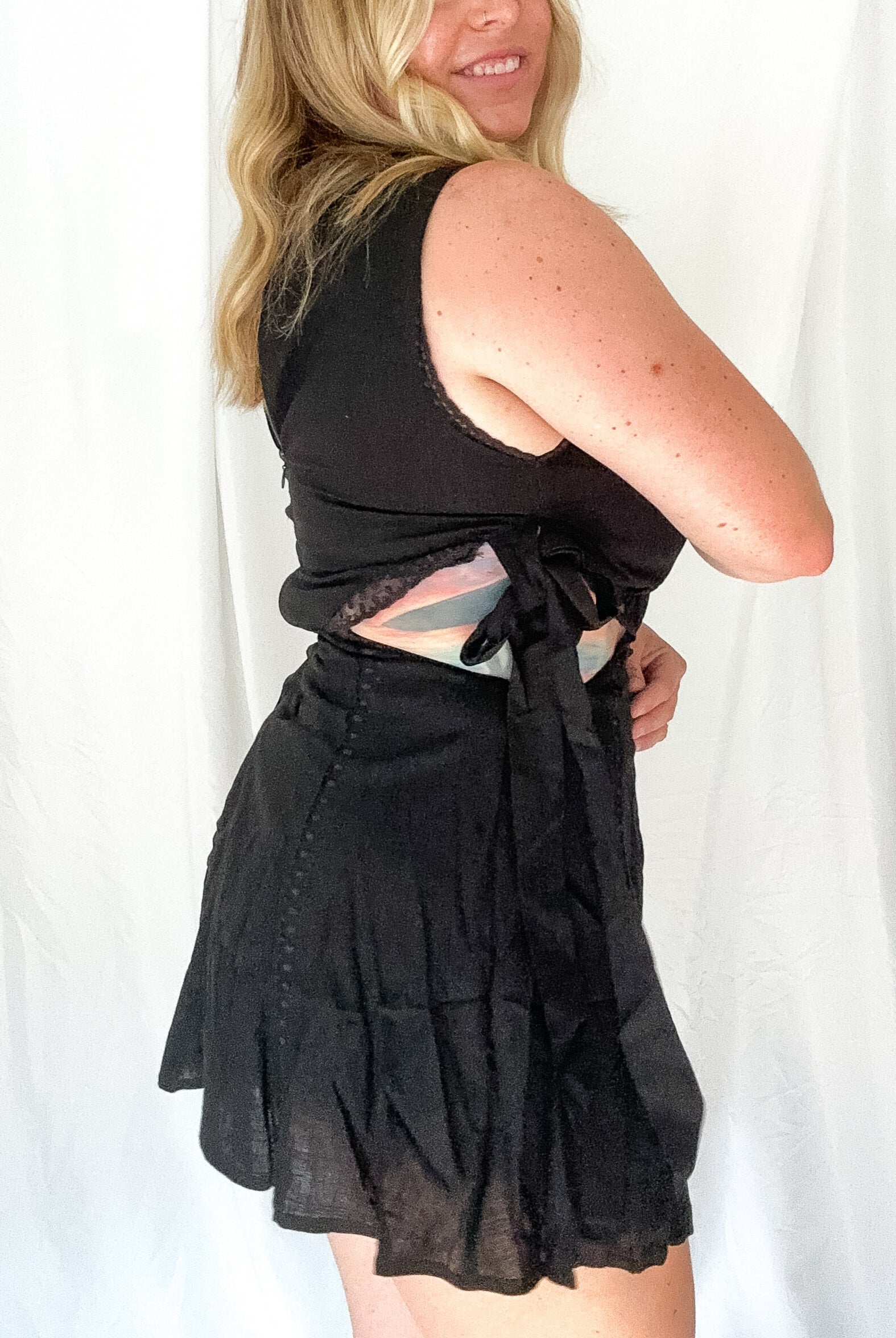 Woman wearing a black sleeveless top and skirt against a white background