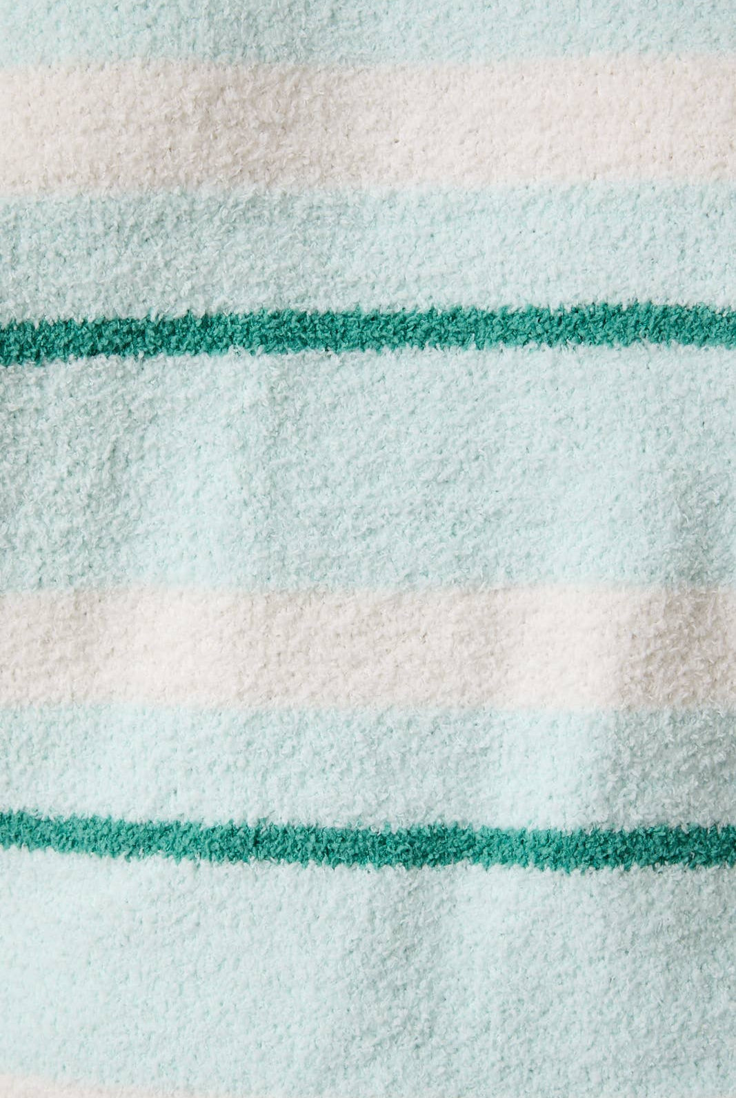 Close-up of a fabric with green and white stripes on a light blue background