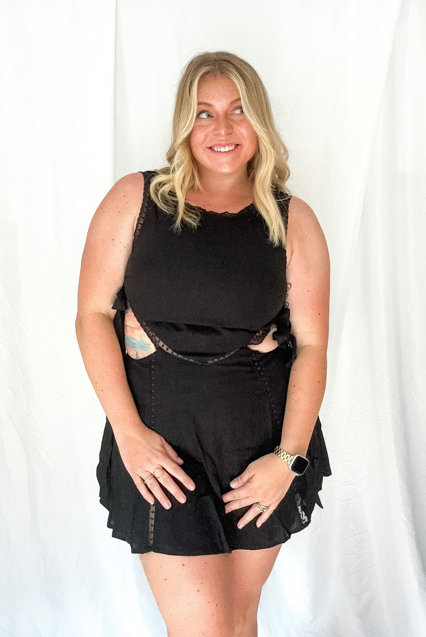 Woman wearing a black sleeveless top and shorts against a white background