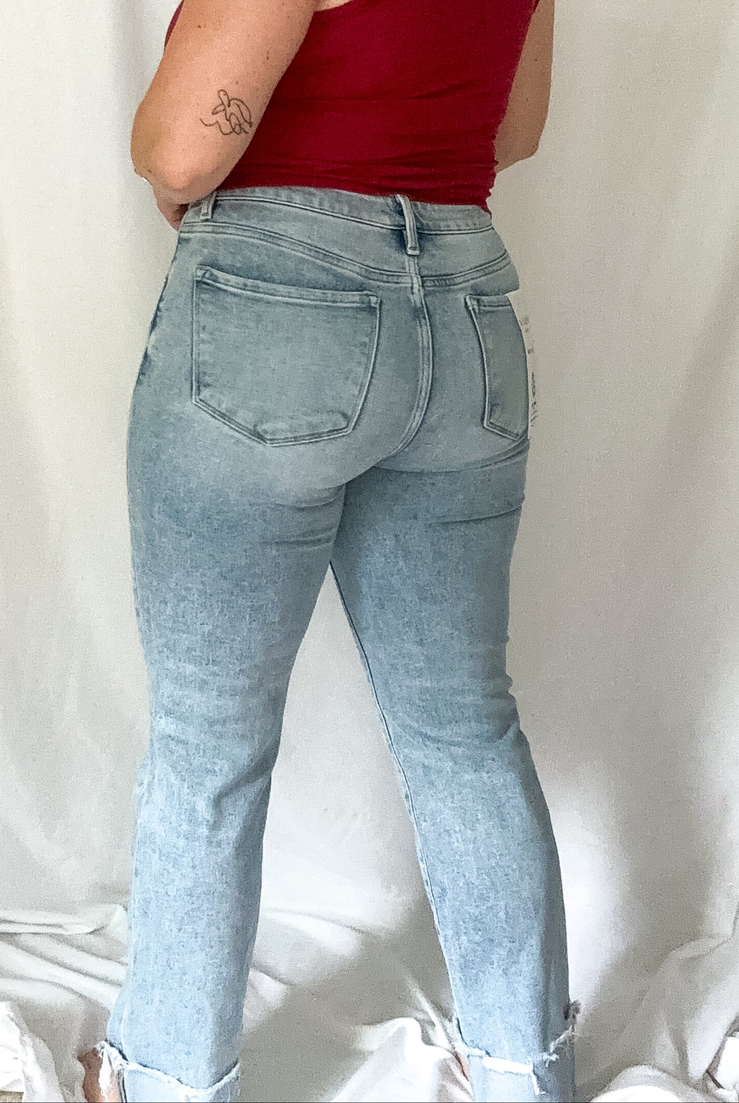Woman wearing a red top and light blue jeans against a white background