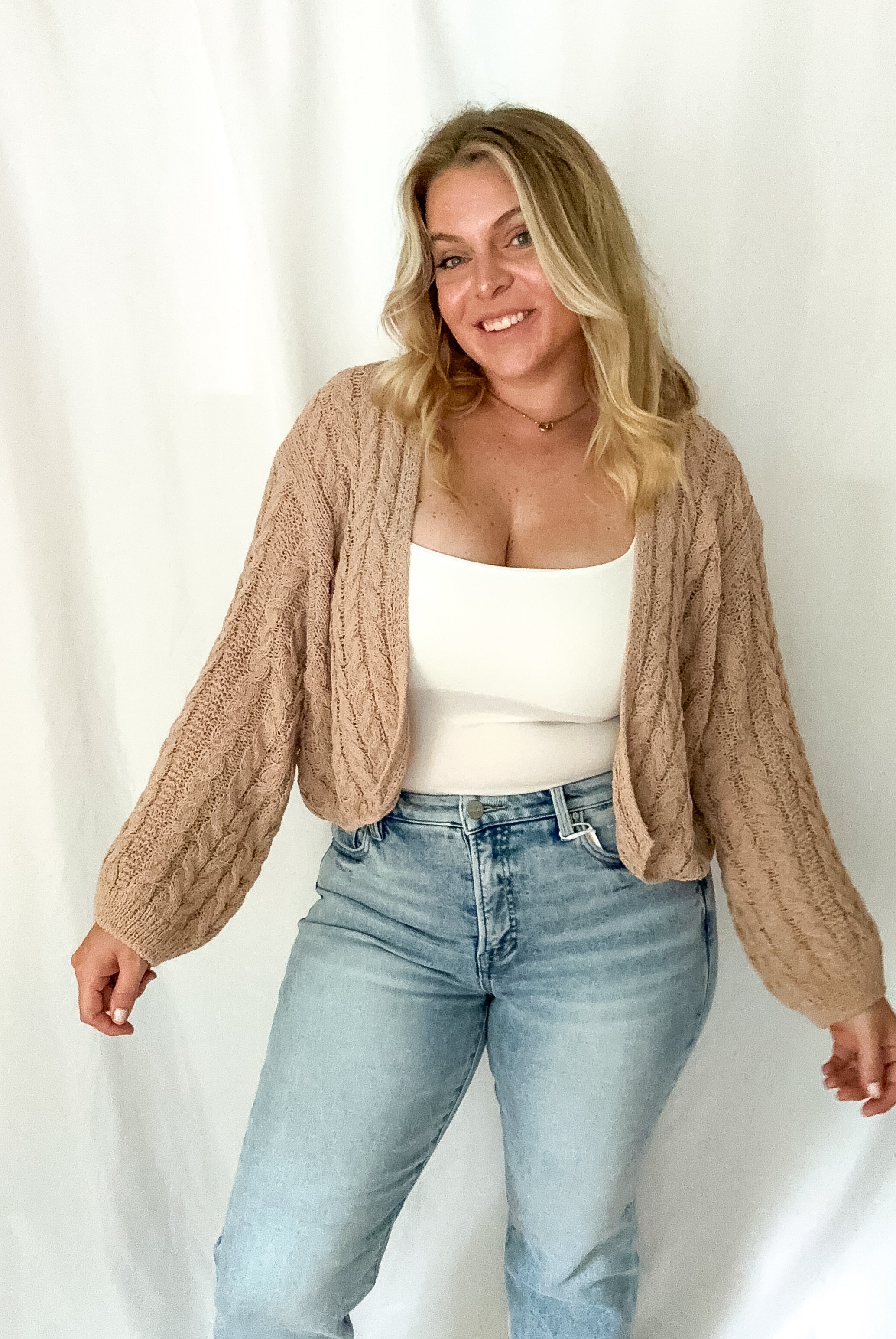 Tan cable knit cardigan with an open front and dolman-style sleeves.