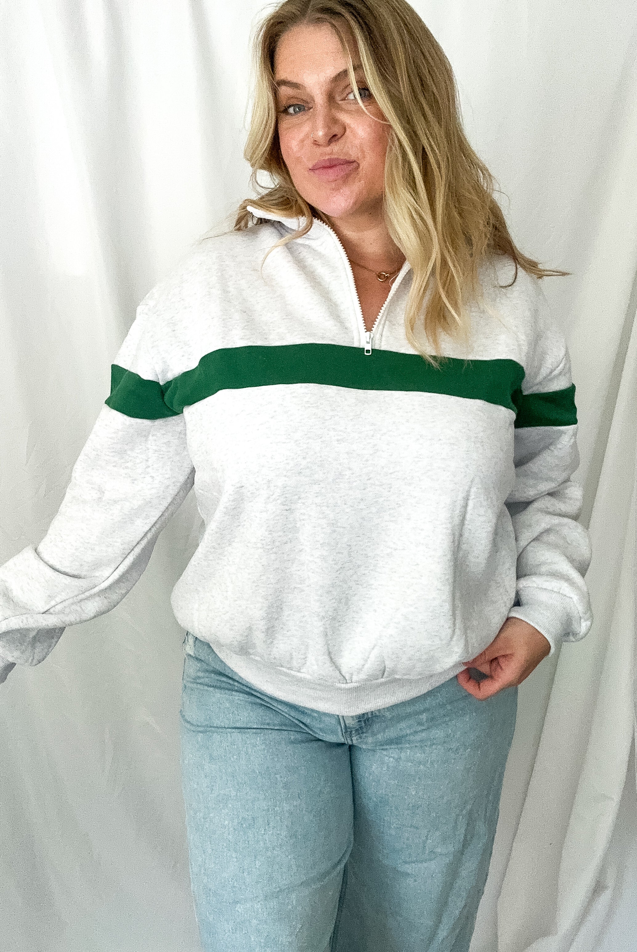 Woman wearing a white sweater with green stripes against a white background