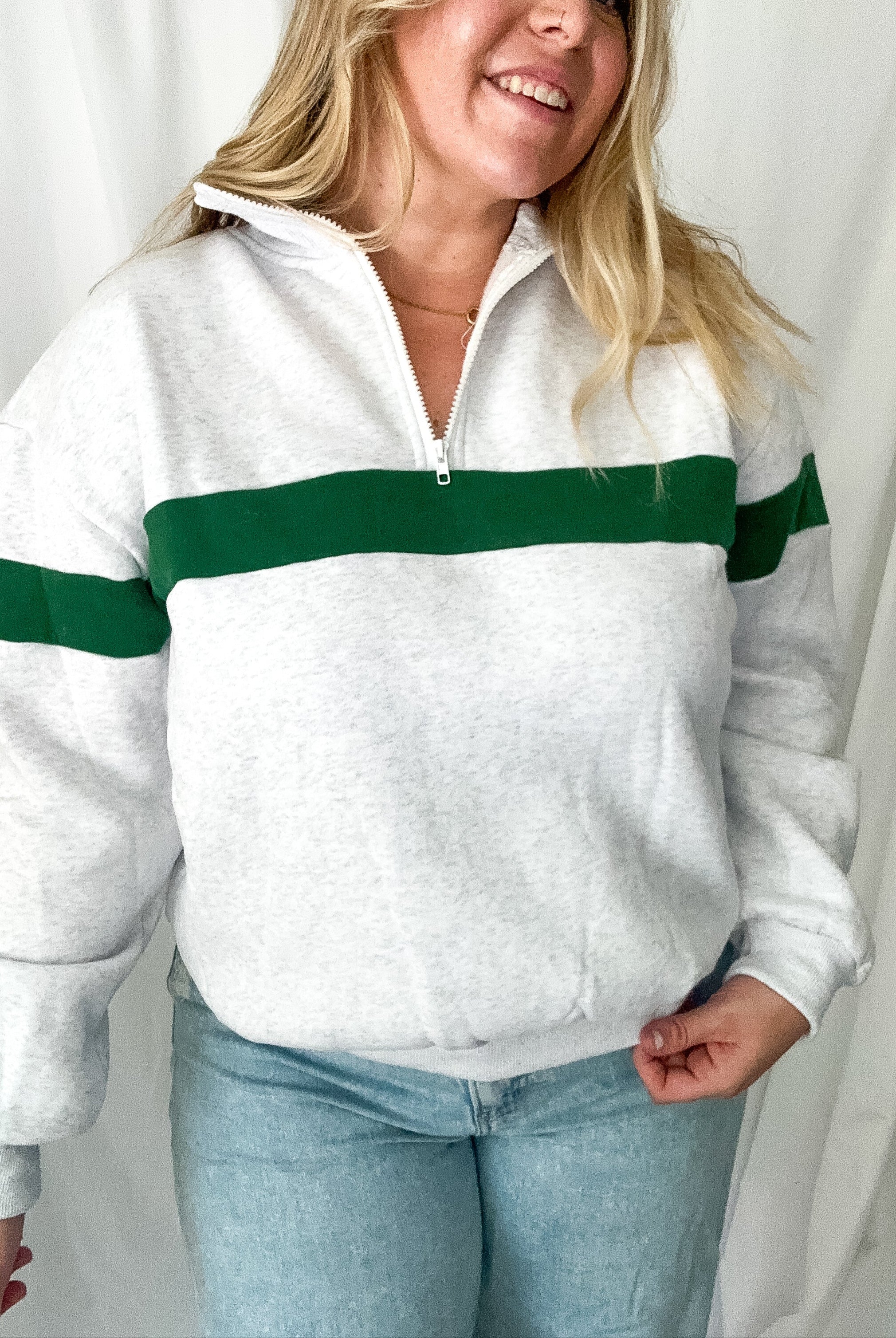 Person wearing a white sweater with green stripes against a plain background