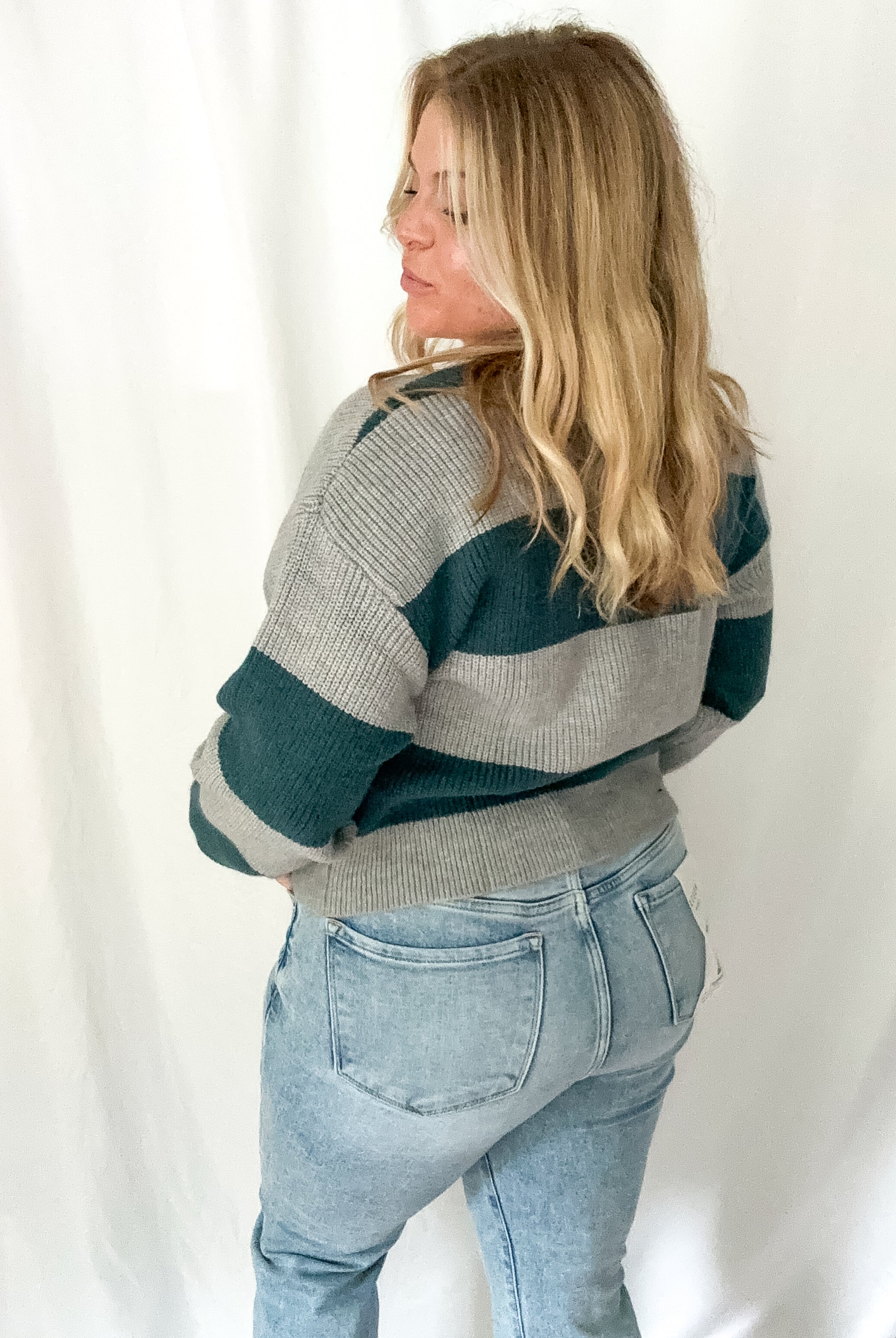 Person wearing a striped sweater and jeans against a white background
