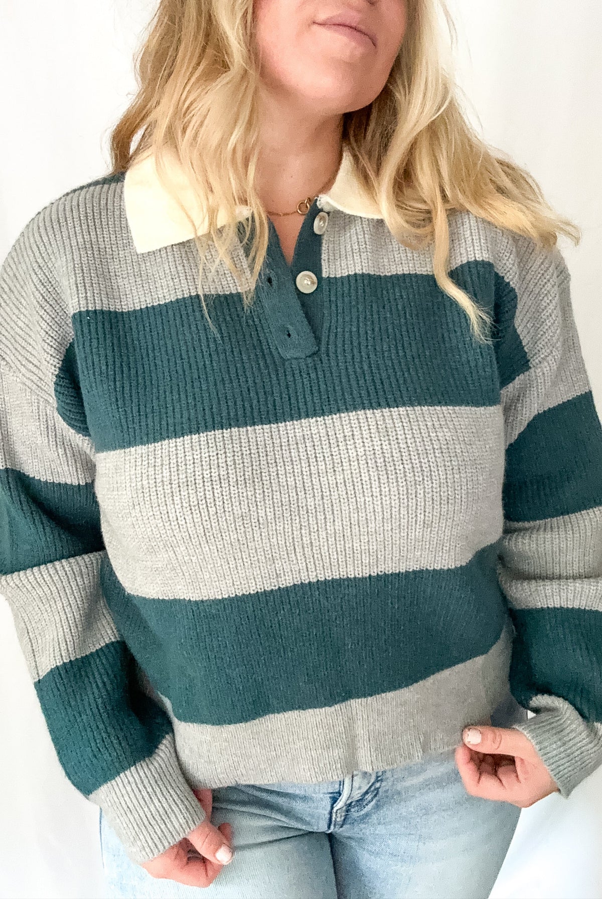 Person wearing a striped sweater with green and gray horizontal stripes on a white background