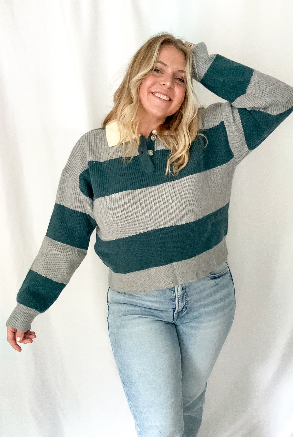 Woman wearing a striped sweater and jeans against a white background