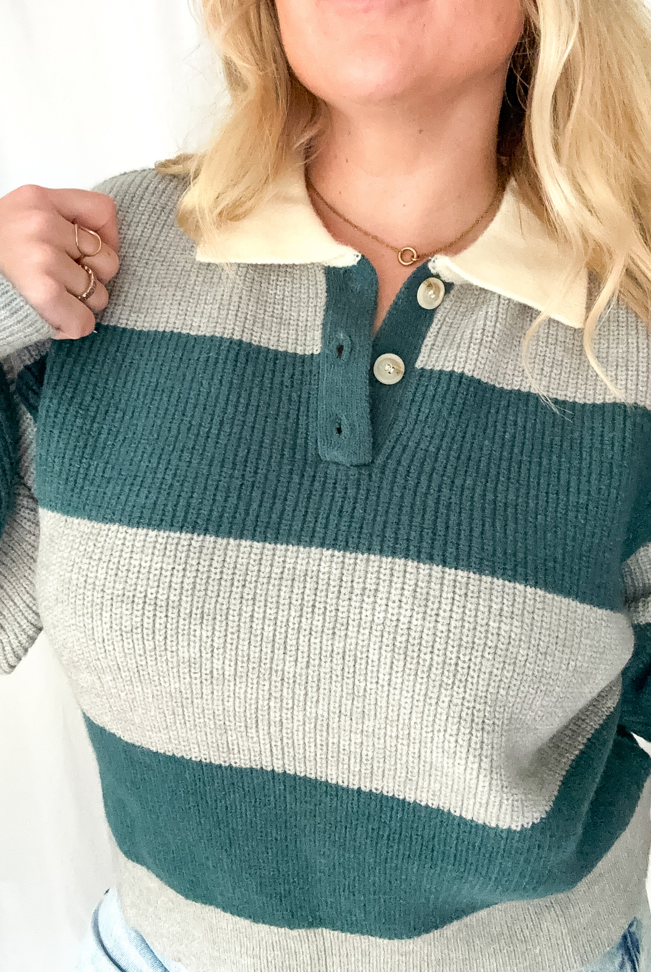 Person wearing a striped sweater with green, gray, and beige colors.