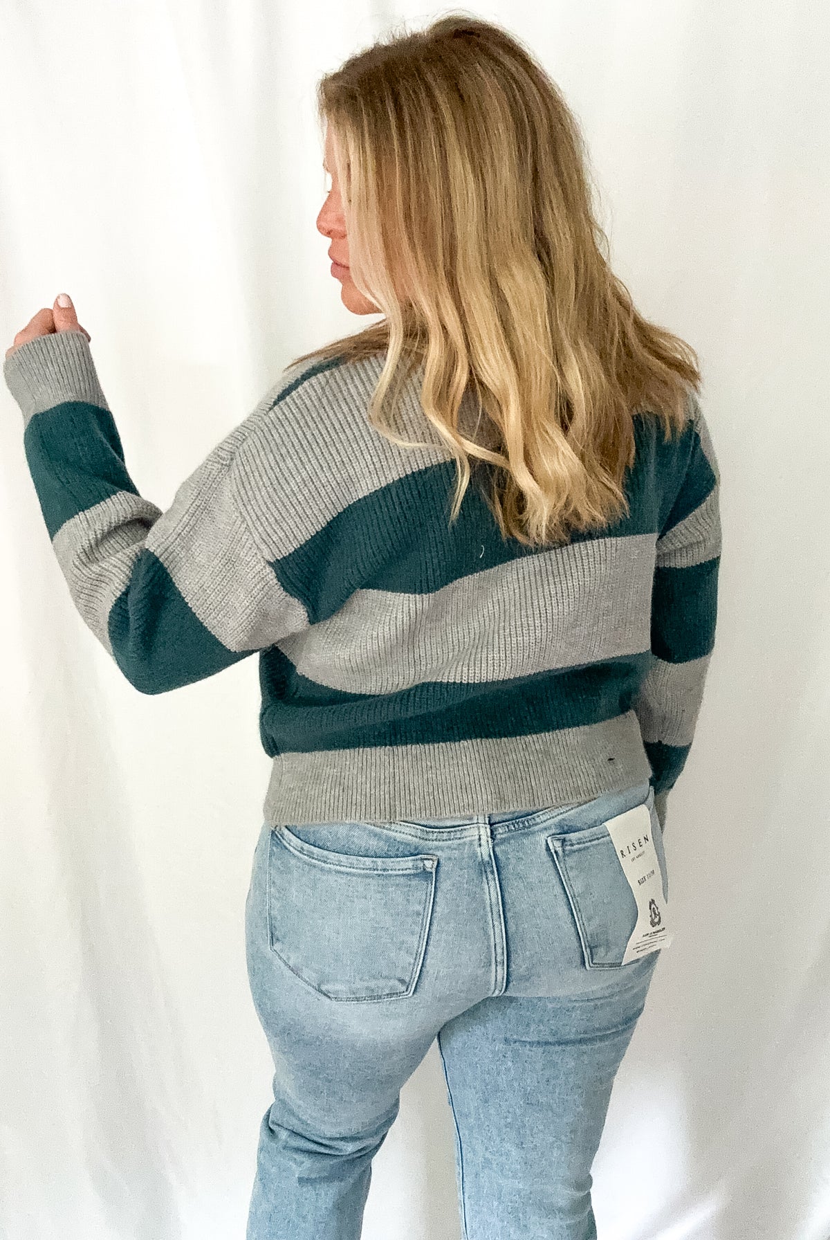 Person wearing a striped sweater and jeans against a white background