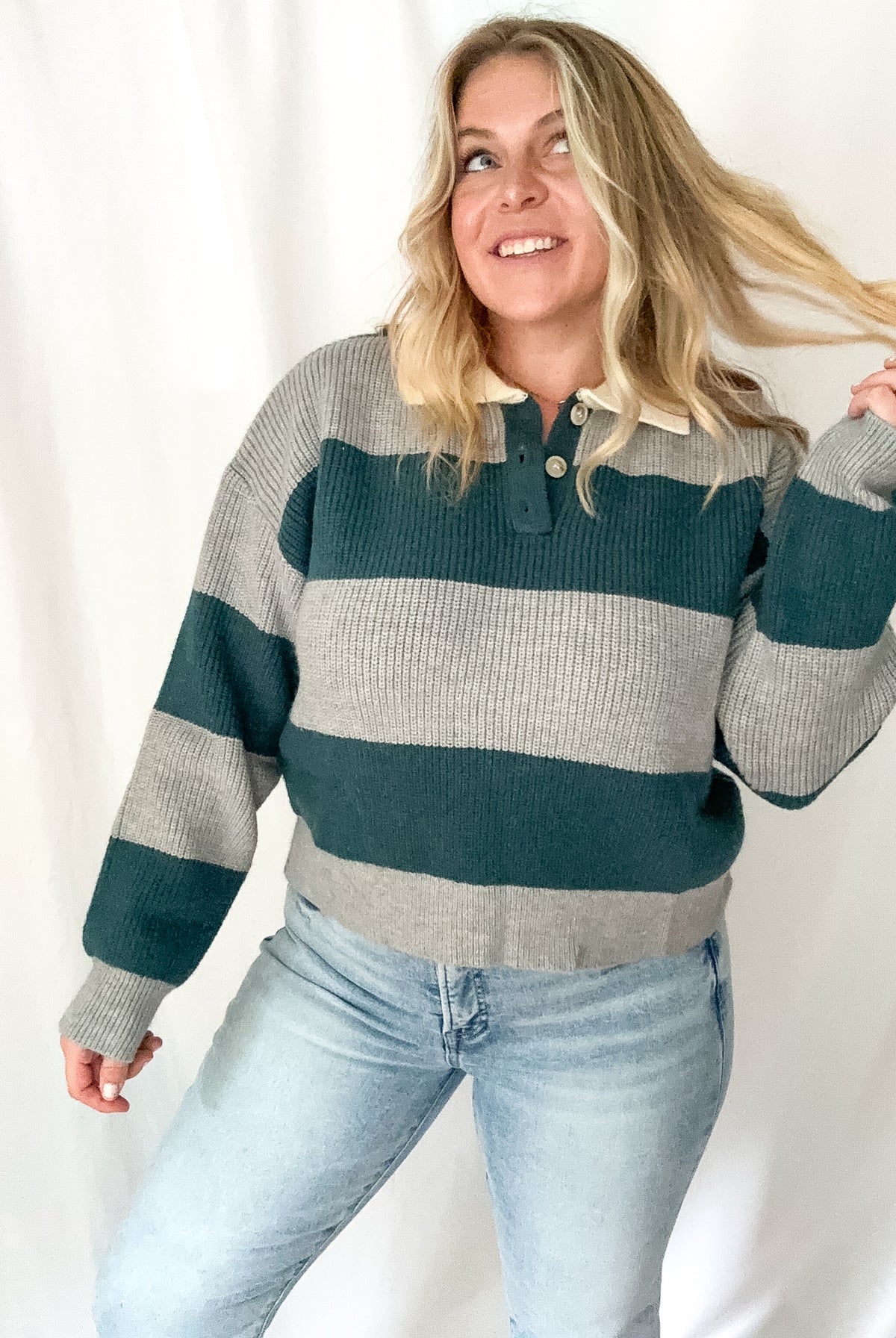 Woman wearing a striped sweater and jeans against a white background