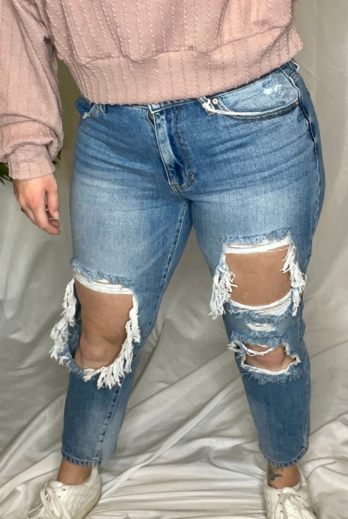 High rise boyfriend jeans in medium wash blue with distressed detailing and a relaxed fit.