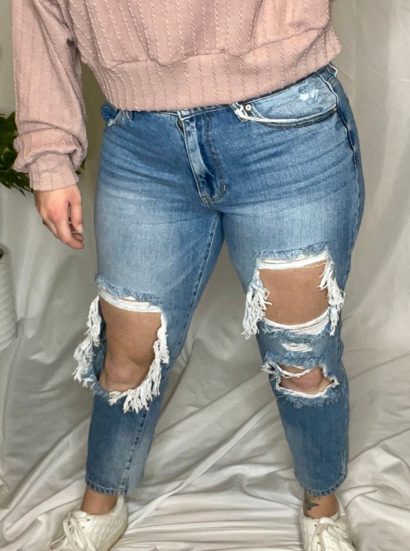 High rise boyfriend jeans in medium wash blue with distressed detailing and a relaxed fit.