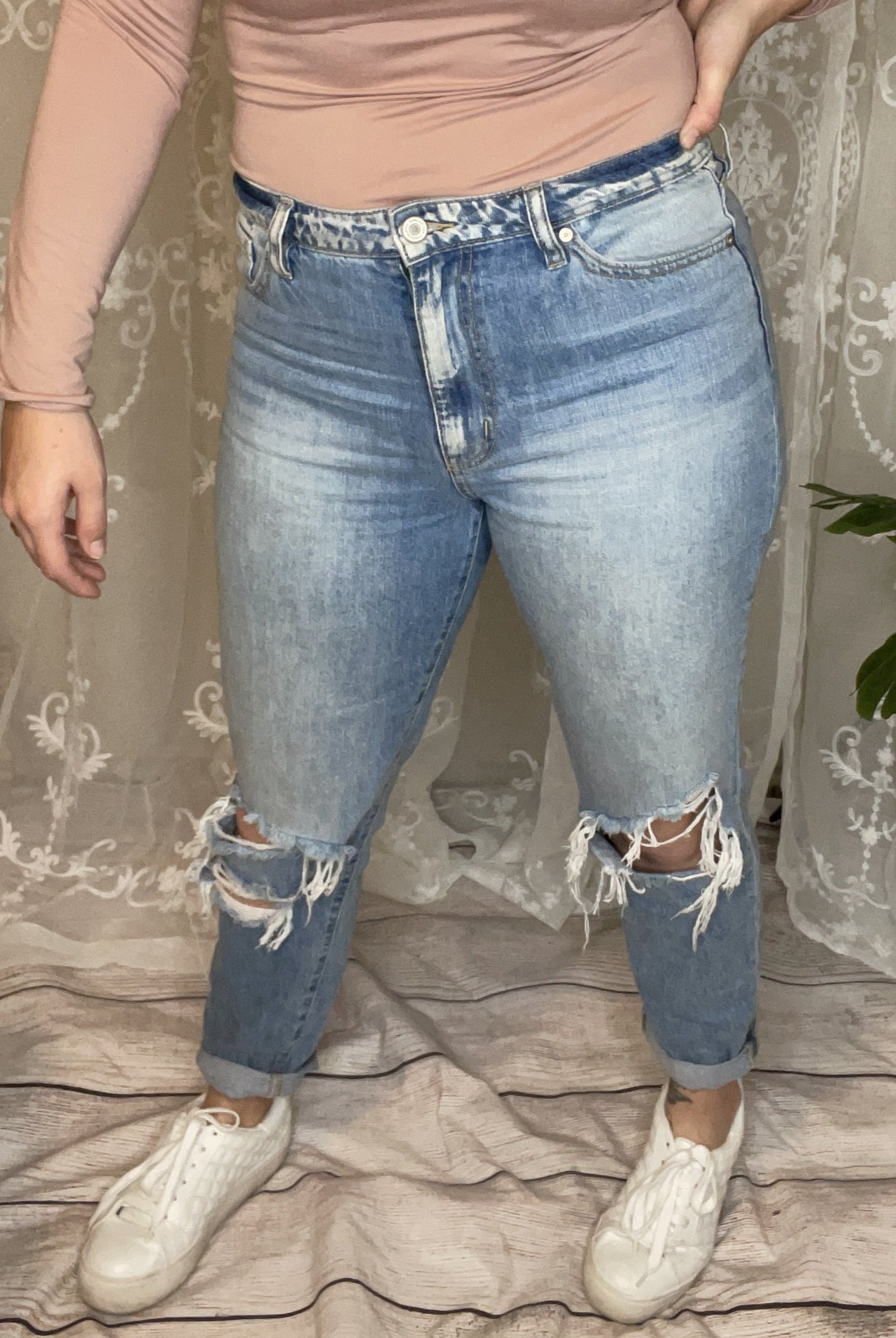 High-rise light wash denim jeans with distressed knees and a cuffed hem.