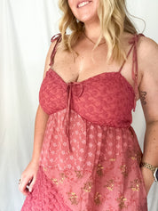 Woman wearing a pink lace dress with a white background