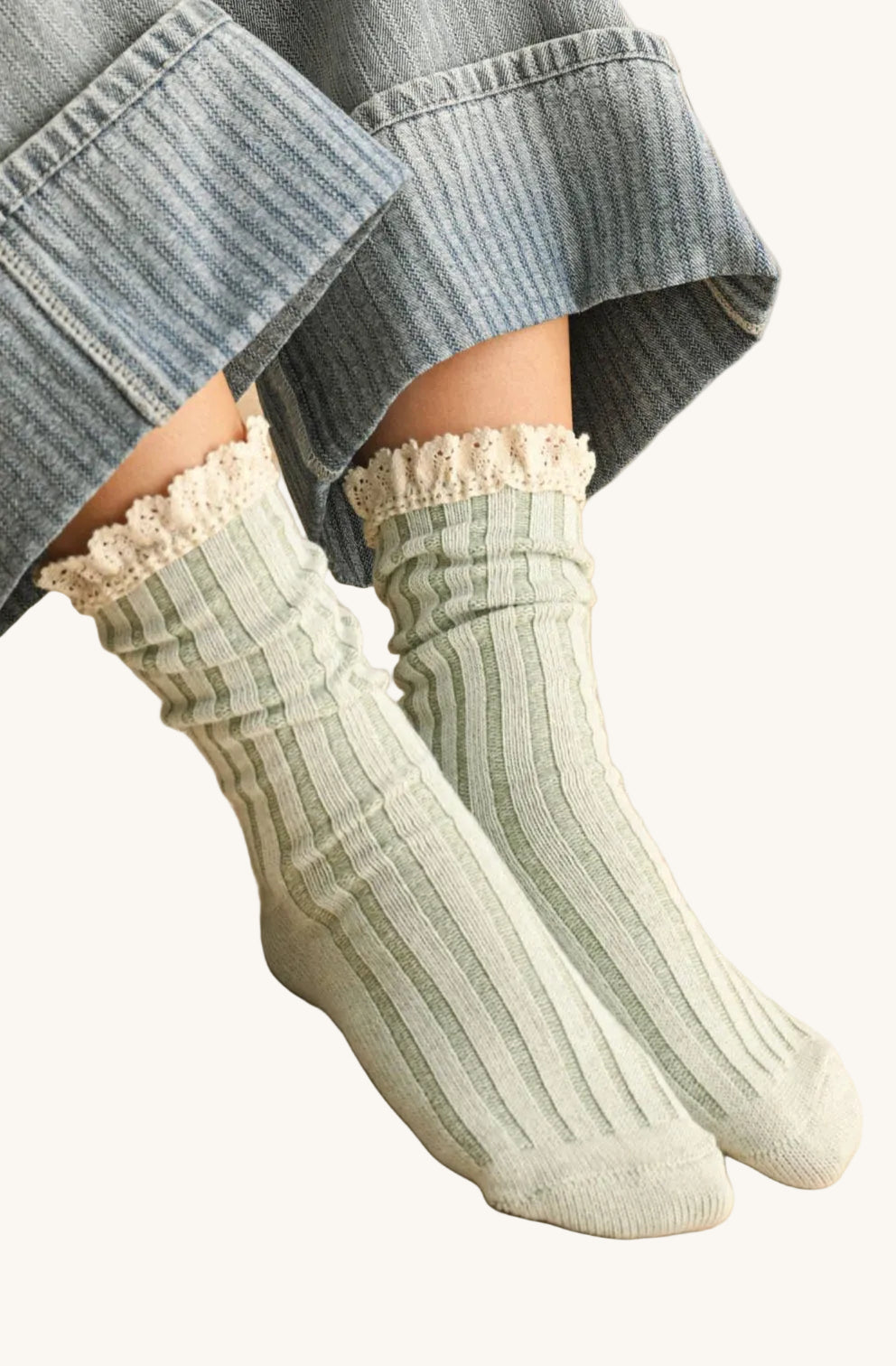 Person wearing green ribbed socks with lace trim on a stone floor.