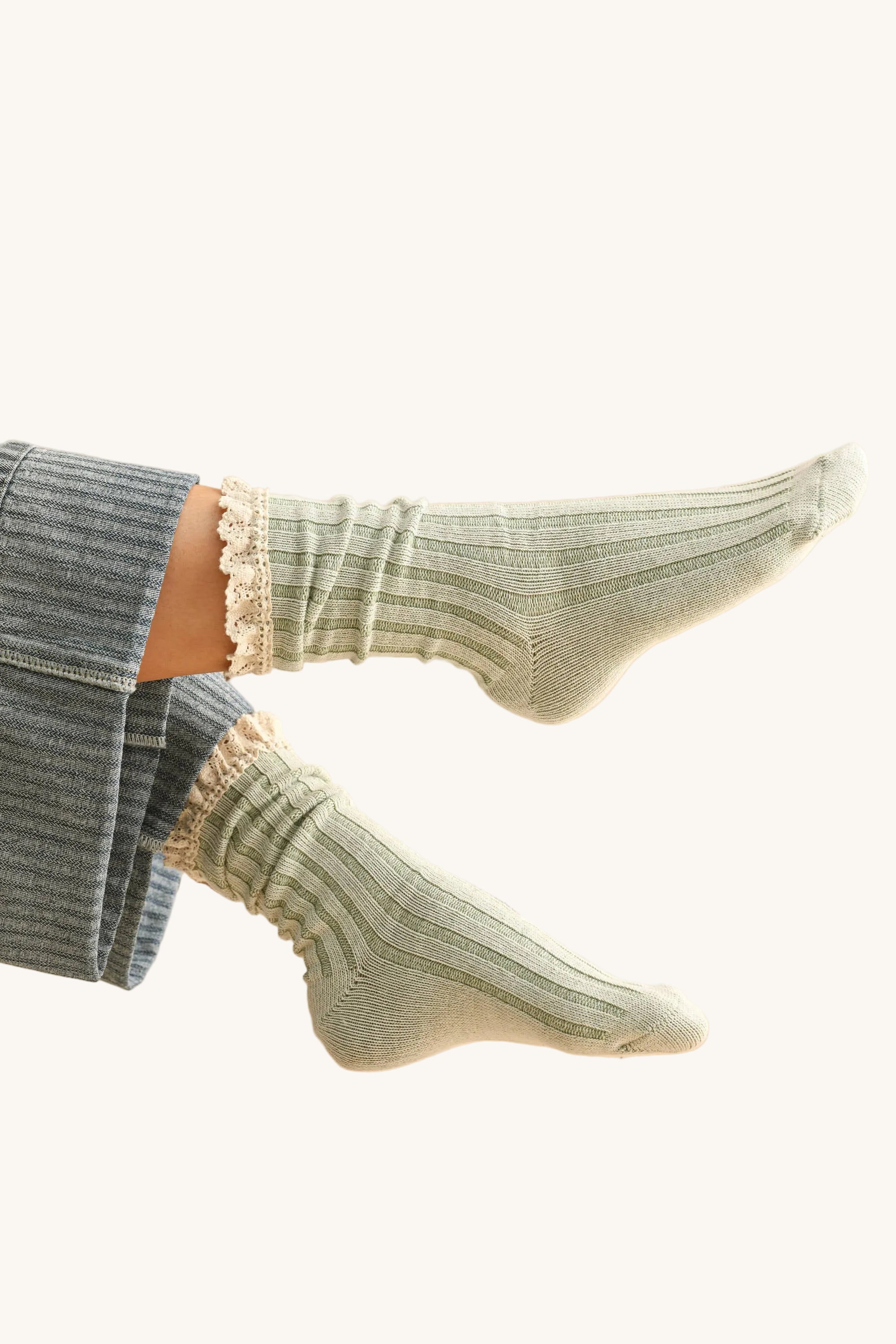 Green socks with ruffled top worn by a person on a beige background