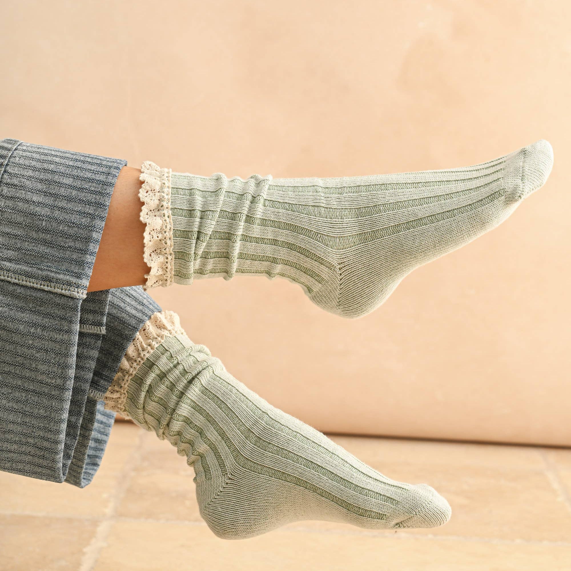 Green socks with ruffled top worn by a person on a beige background