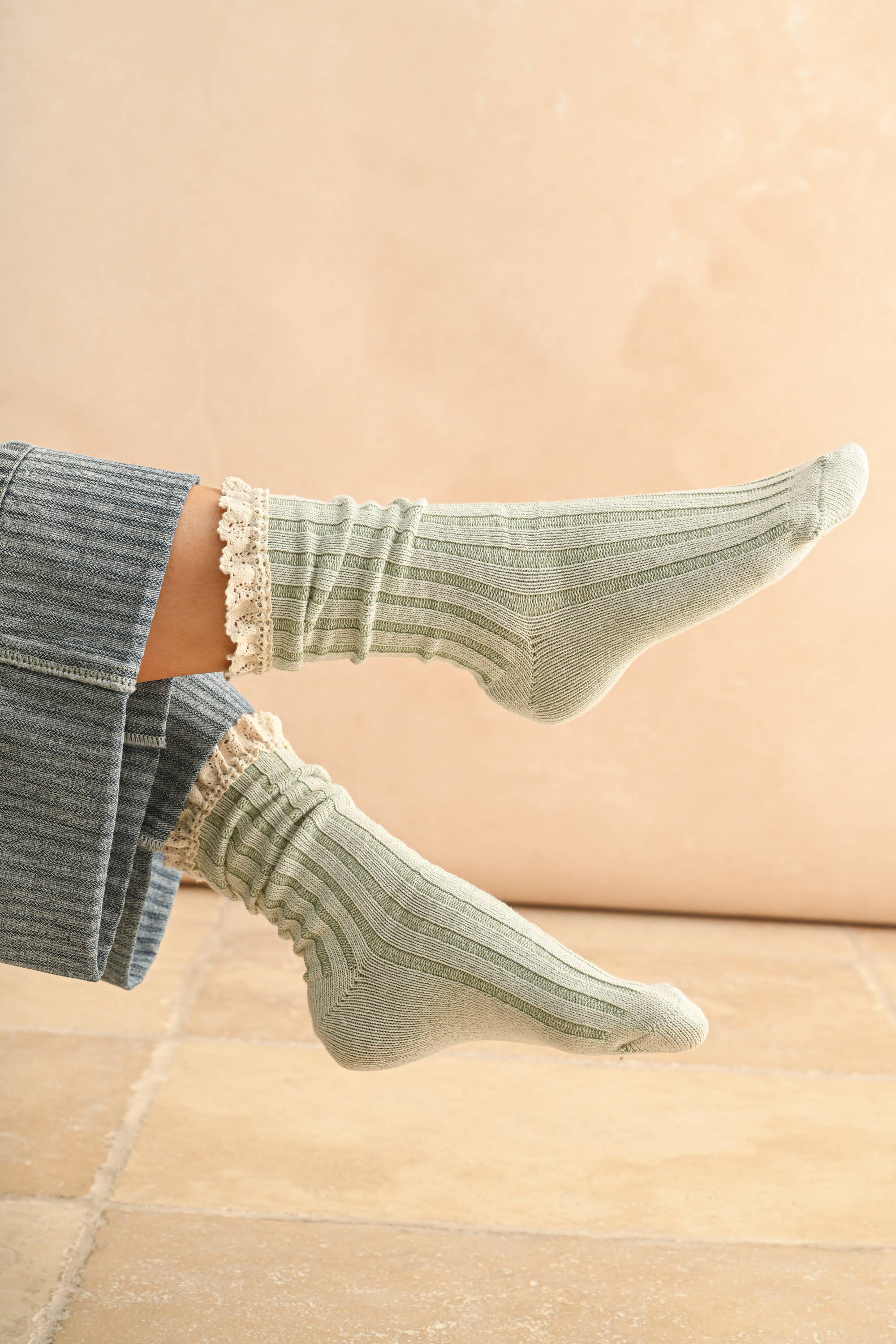 Green socks with ruffled top worn by a person on a beige background