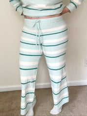 Person wearing a matching striped sweater and pants set in a room with a neutral background.