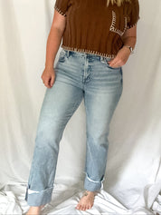 Woman wearing a brown top and light blue jeans against a white background
