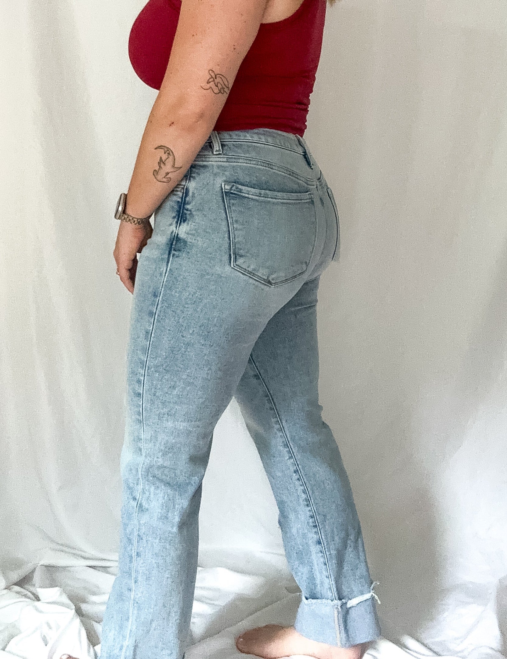 Woman wearing a red top and light blue jeans against a white background