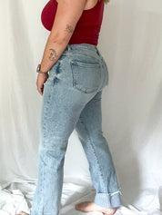 Woman wearing a red top and light blue jeans against a white background