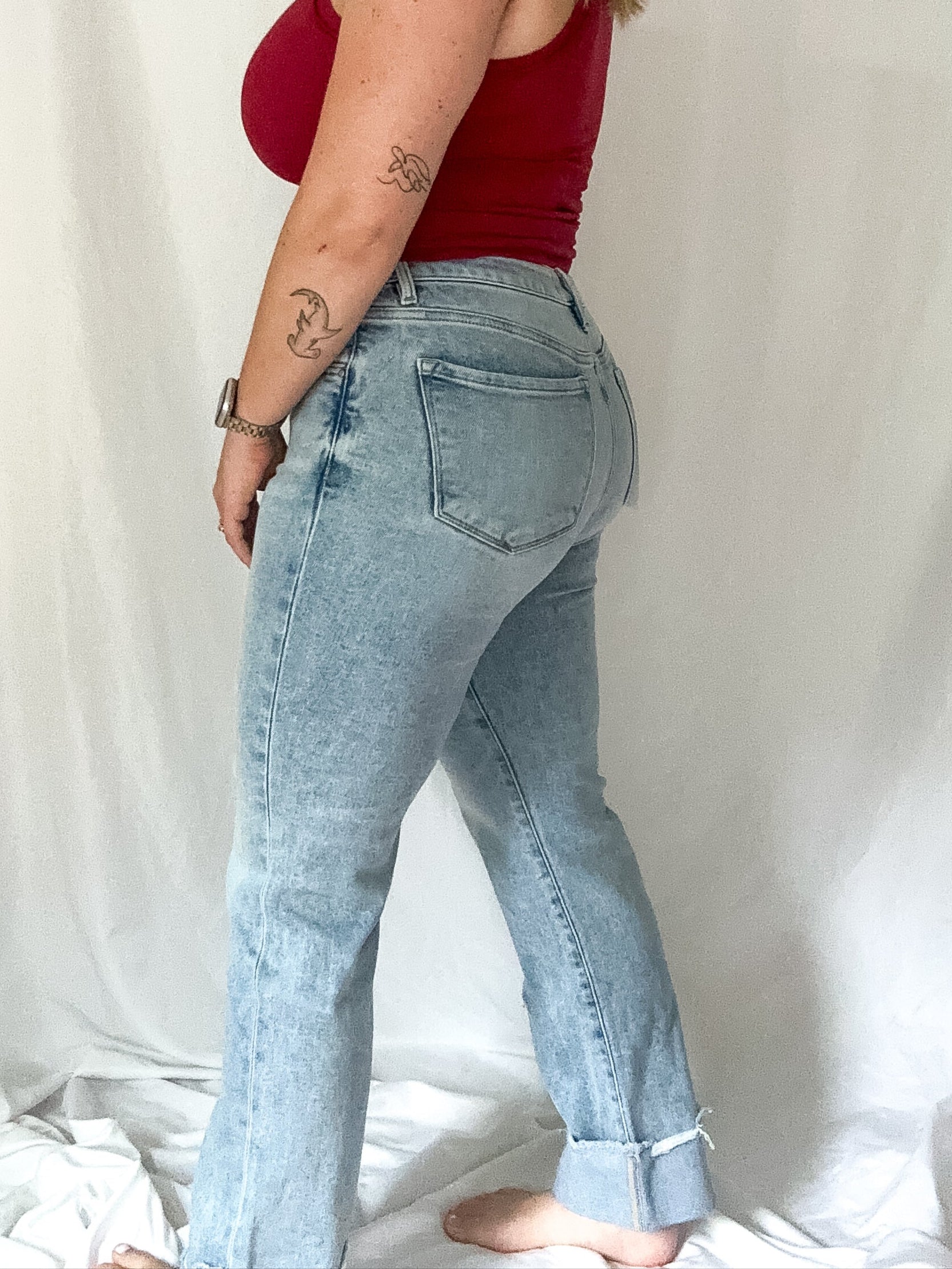 Woman wearing a red top and light blue jeans against a white background