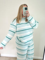 Person wearing a light blue and white striped outfit taking a mirror selfie.
