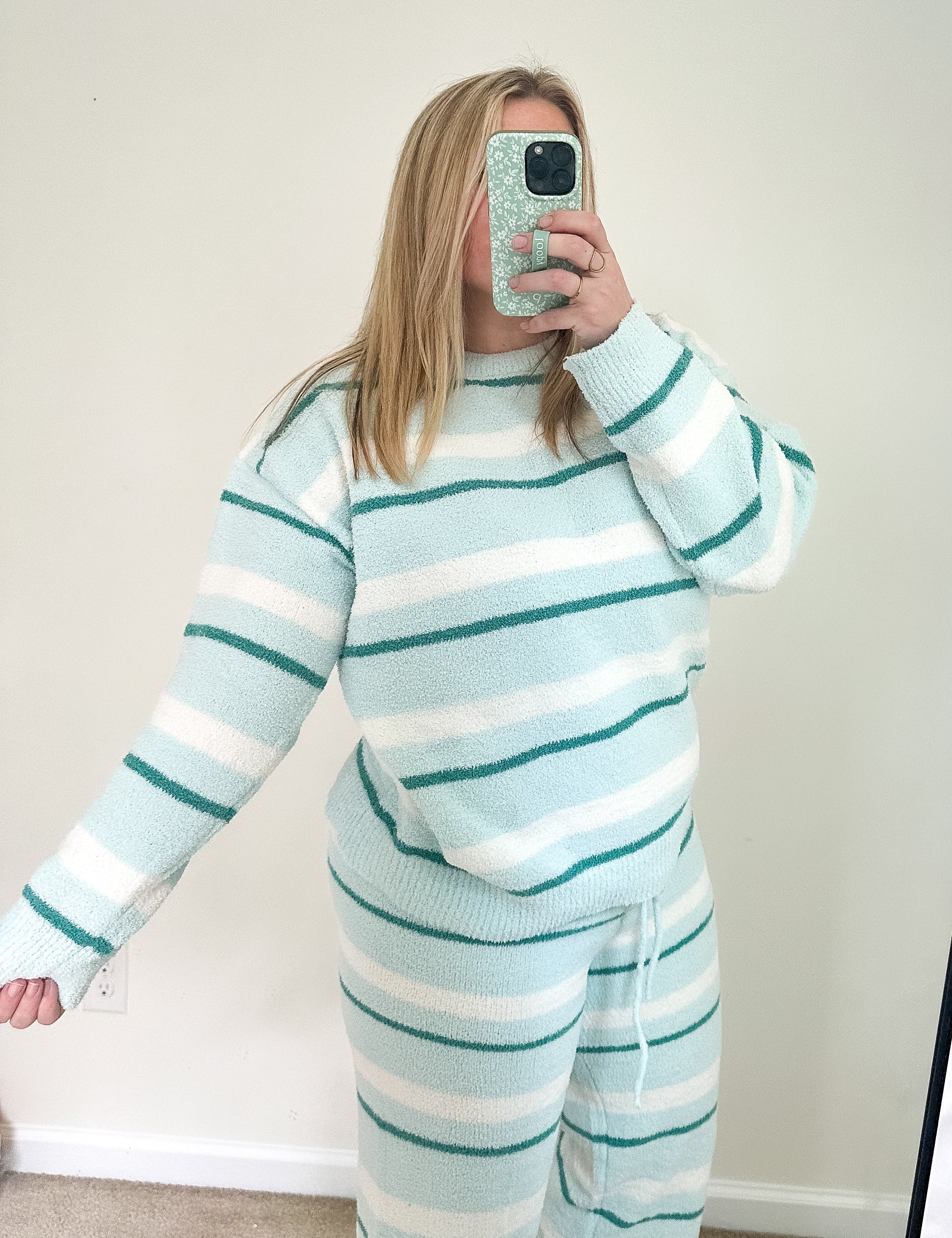 Person wearing a light blue and white striped outfit taking a mirror selfie.