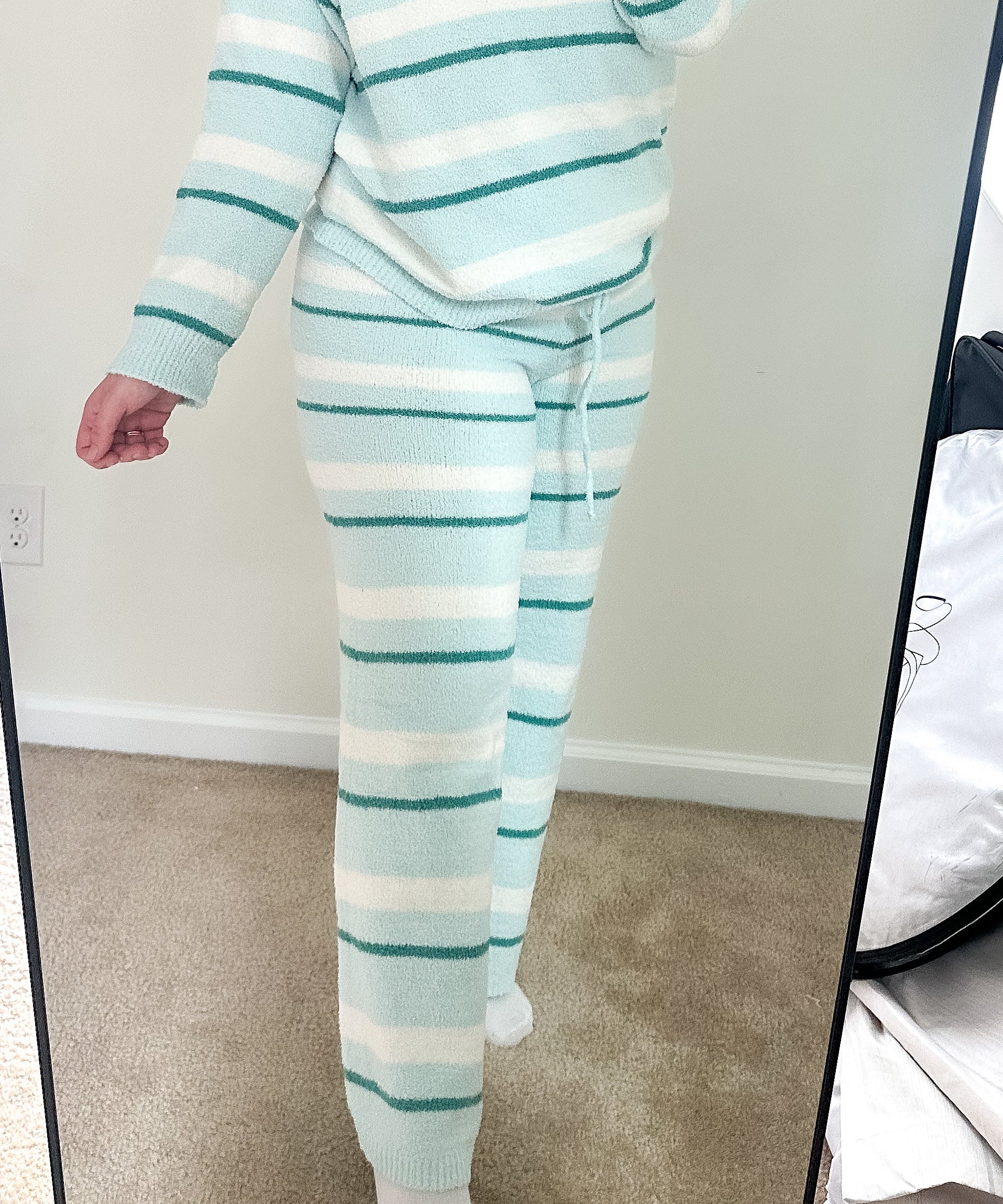 Person wearing a light blue and white striped pajama set taking a mirror selfie.