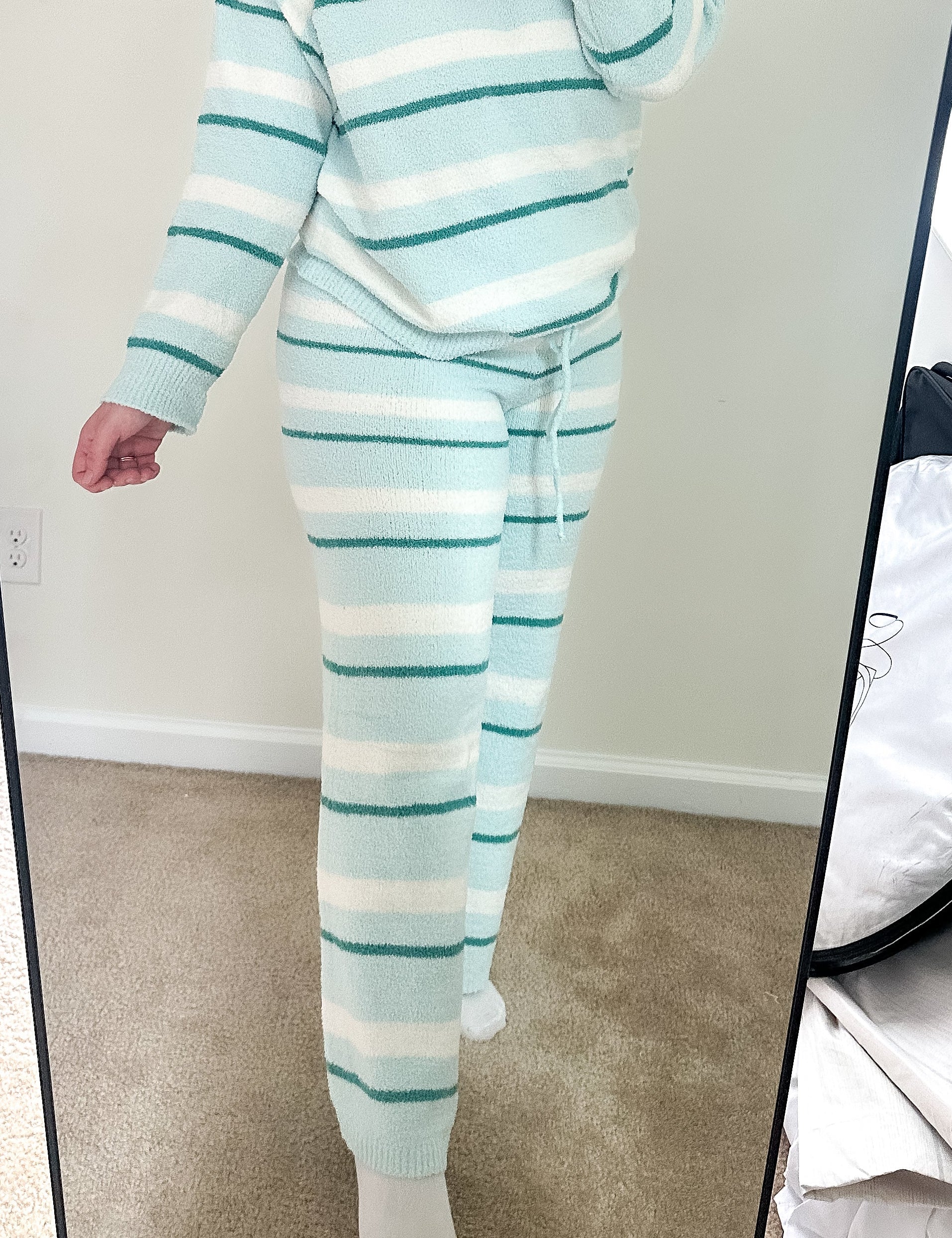 Person wearing a light blue and white striped pajama set taking a mirror selfie.
