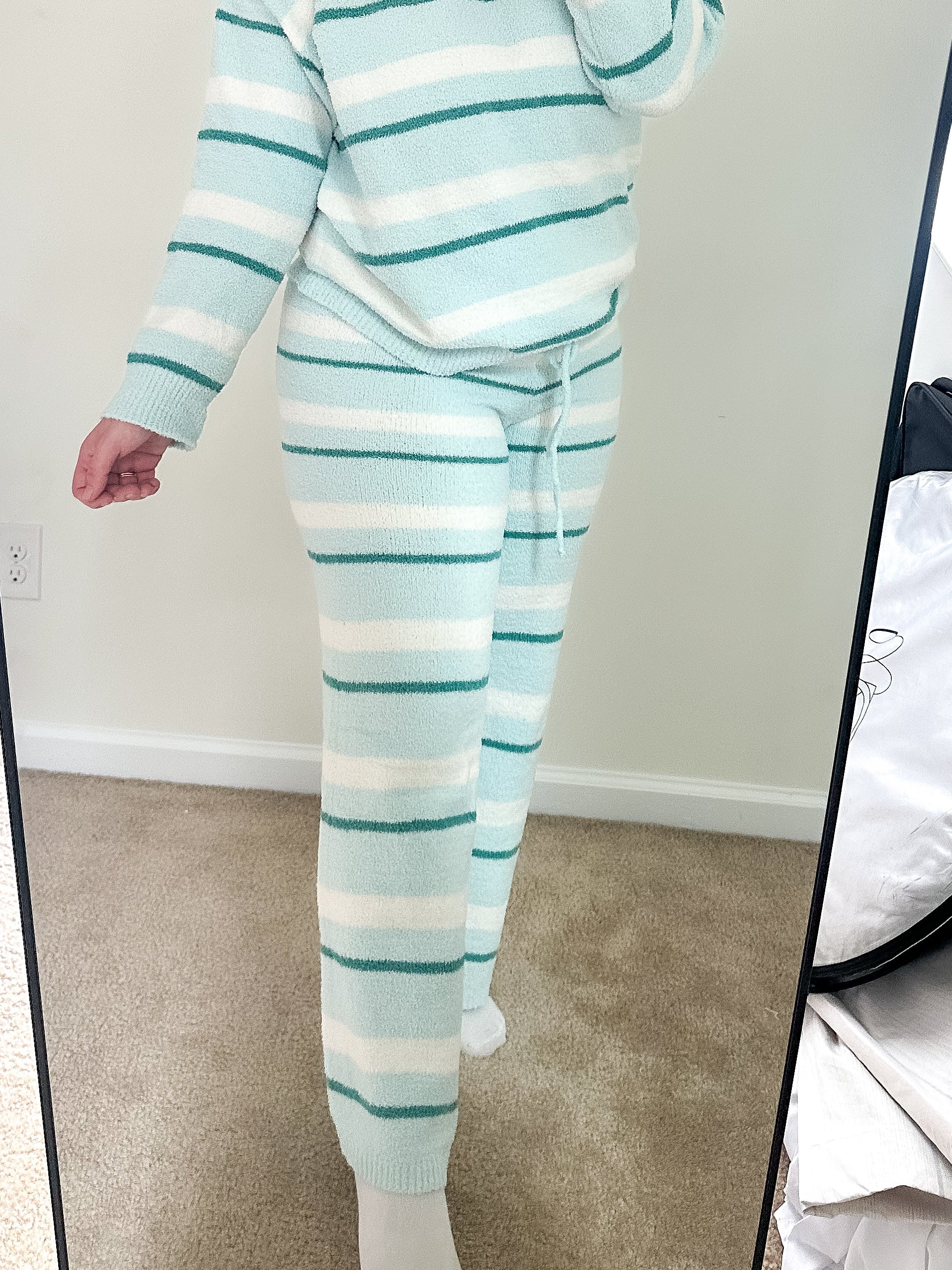 Person wearing a light blue and white striped pajama set taking a mirror selfie.