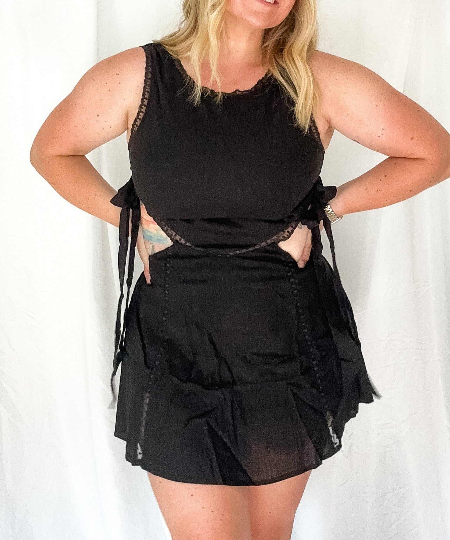 Woman wearing a black outfit with sheer details against a white background