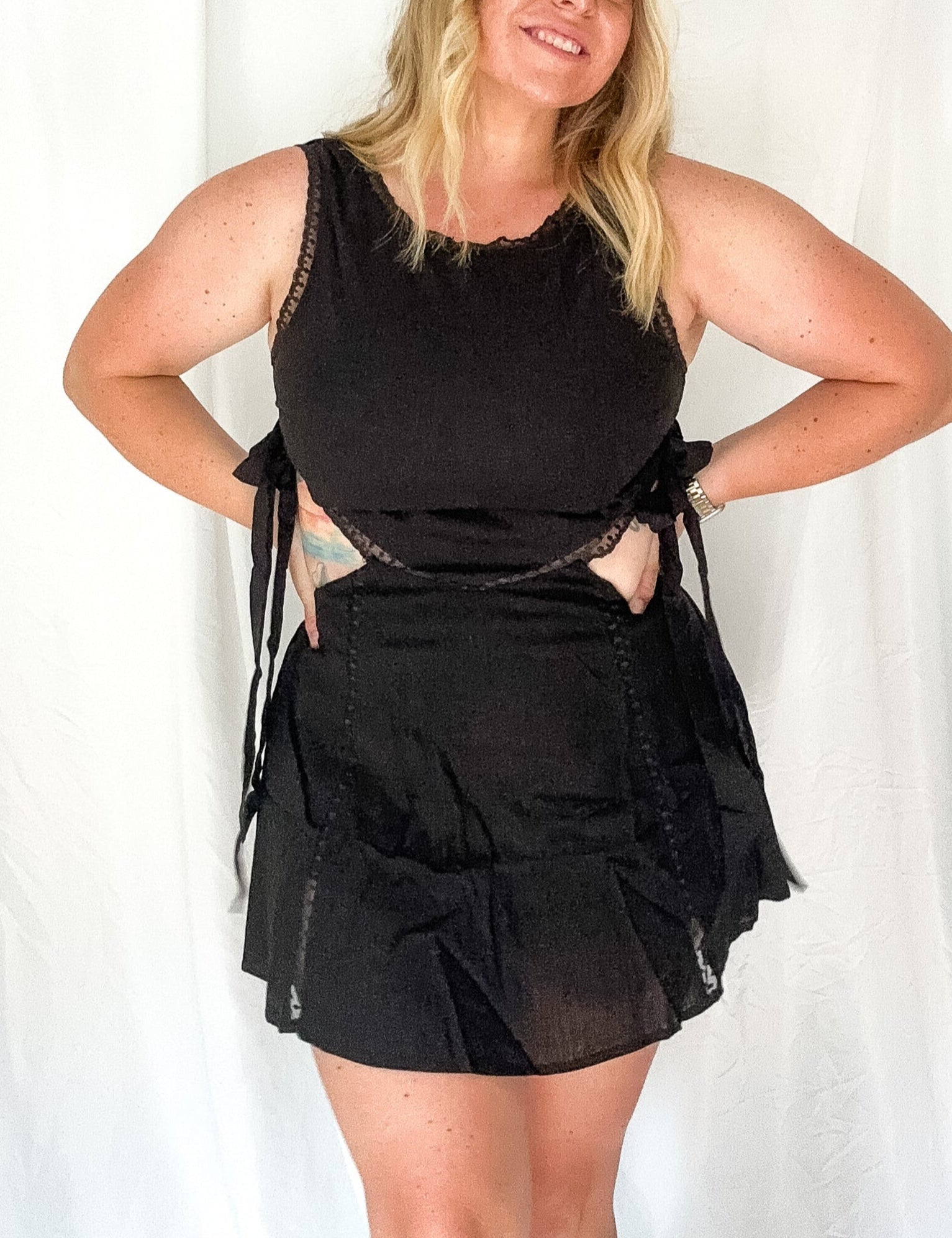 Woman wearing a black outfit with sheer details against a white background