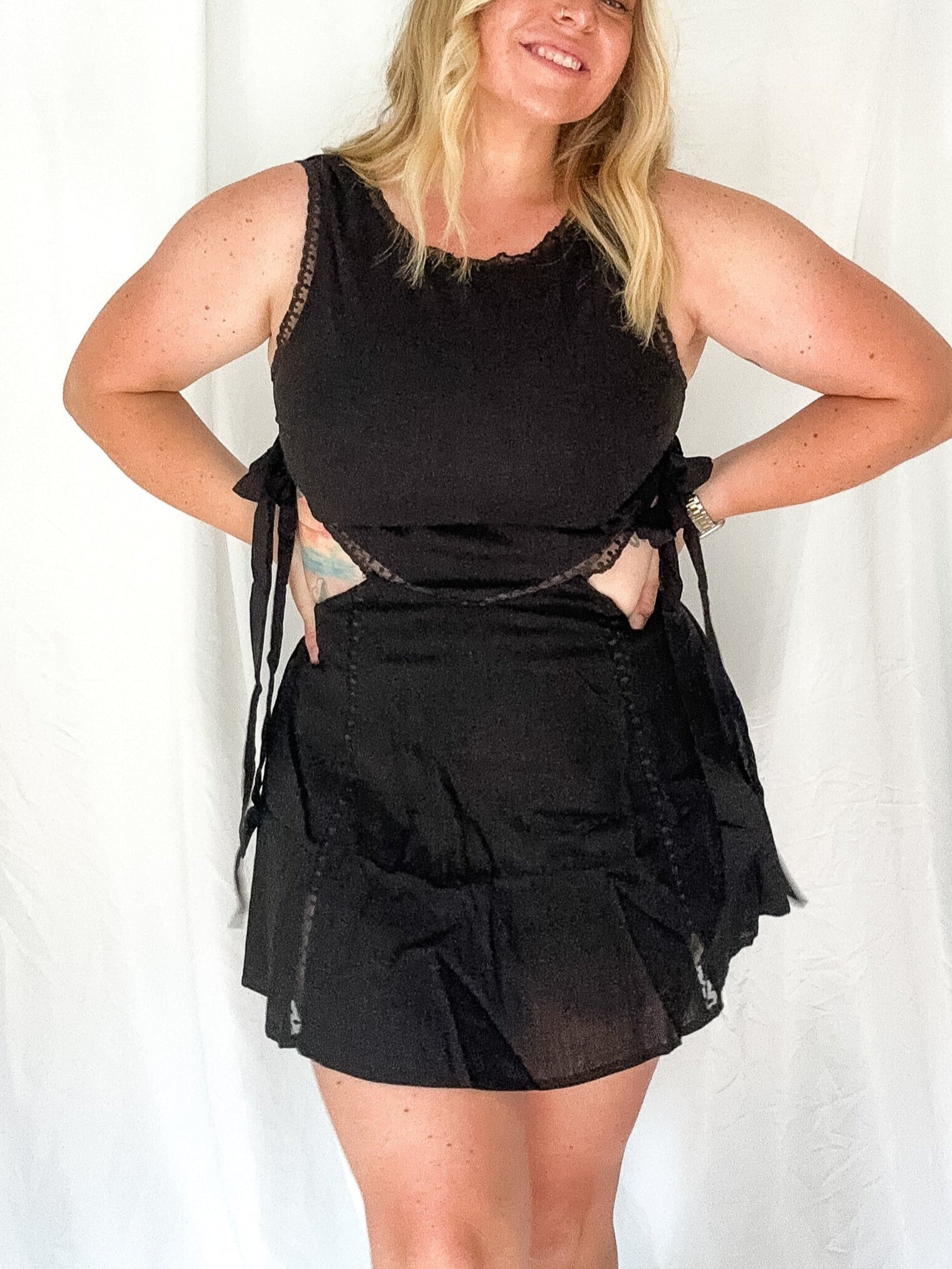 Woman wearing a black outfit with sheer details against a white background