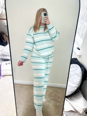 Person wearing a light blue and white striped pajama set taking a mirror selfie.