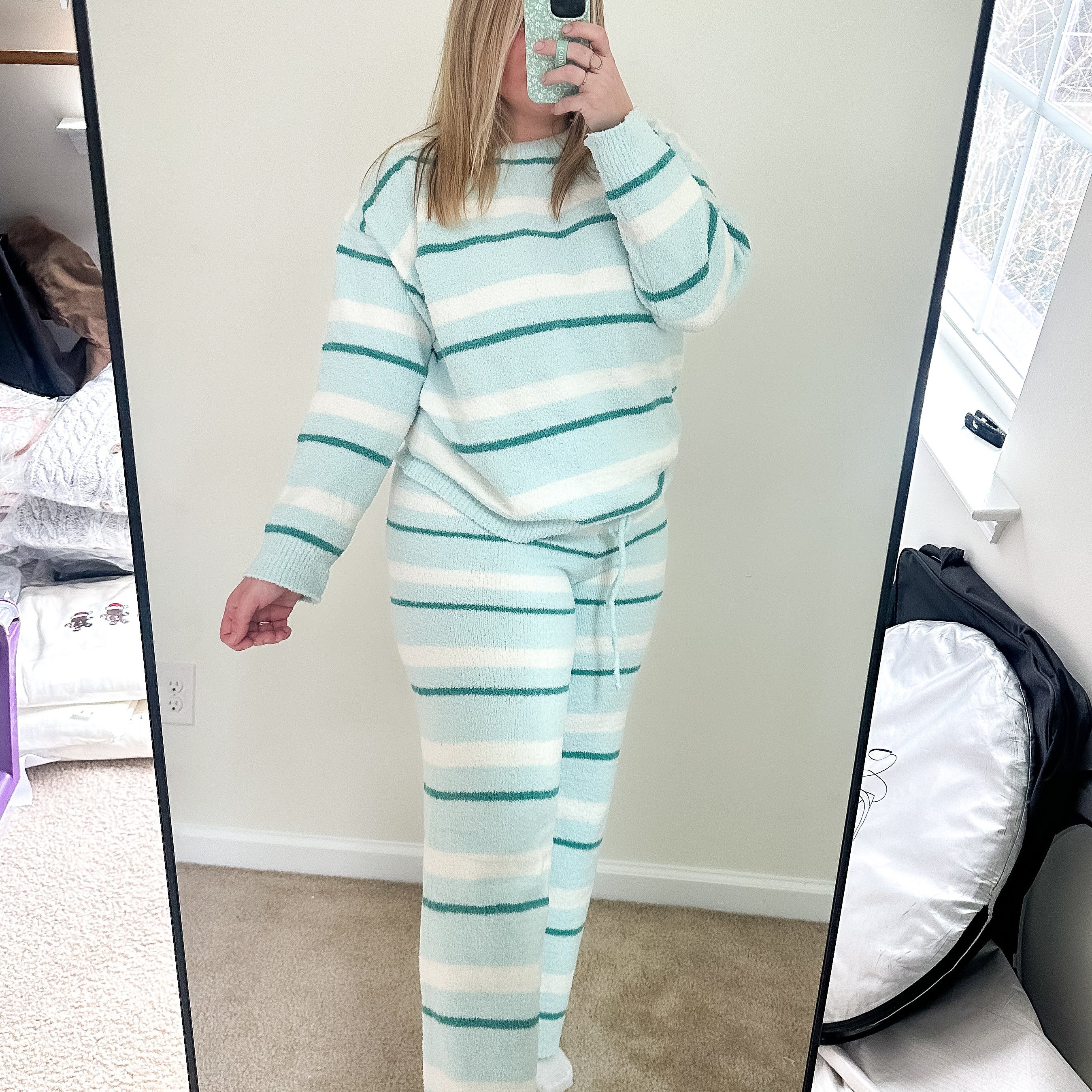 Person wearing a light blue and white striped pajama set taking a mirror selfie.