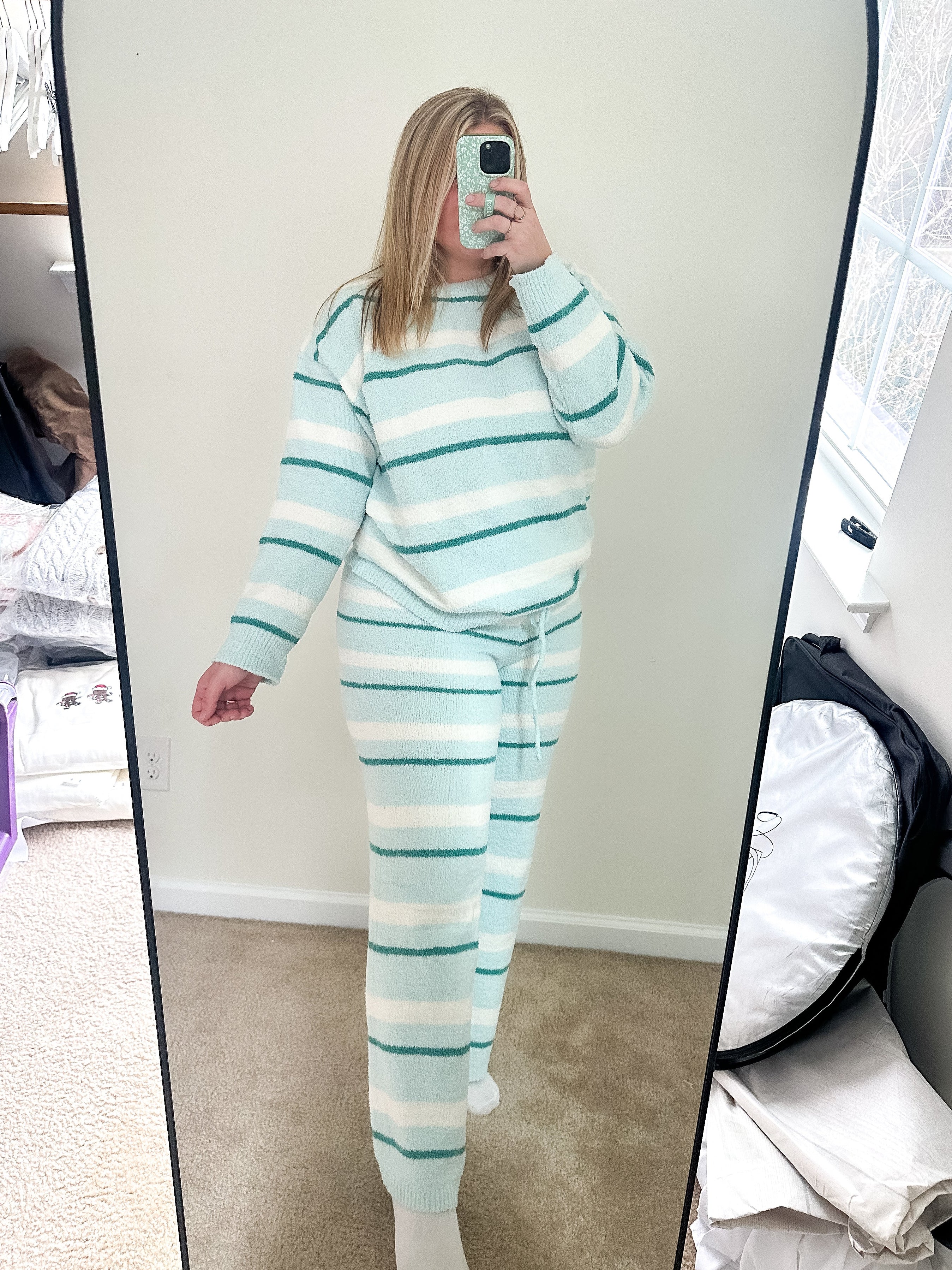 Person wearing a light blue and white striped pajama set taking a mirror selfie.