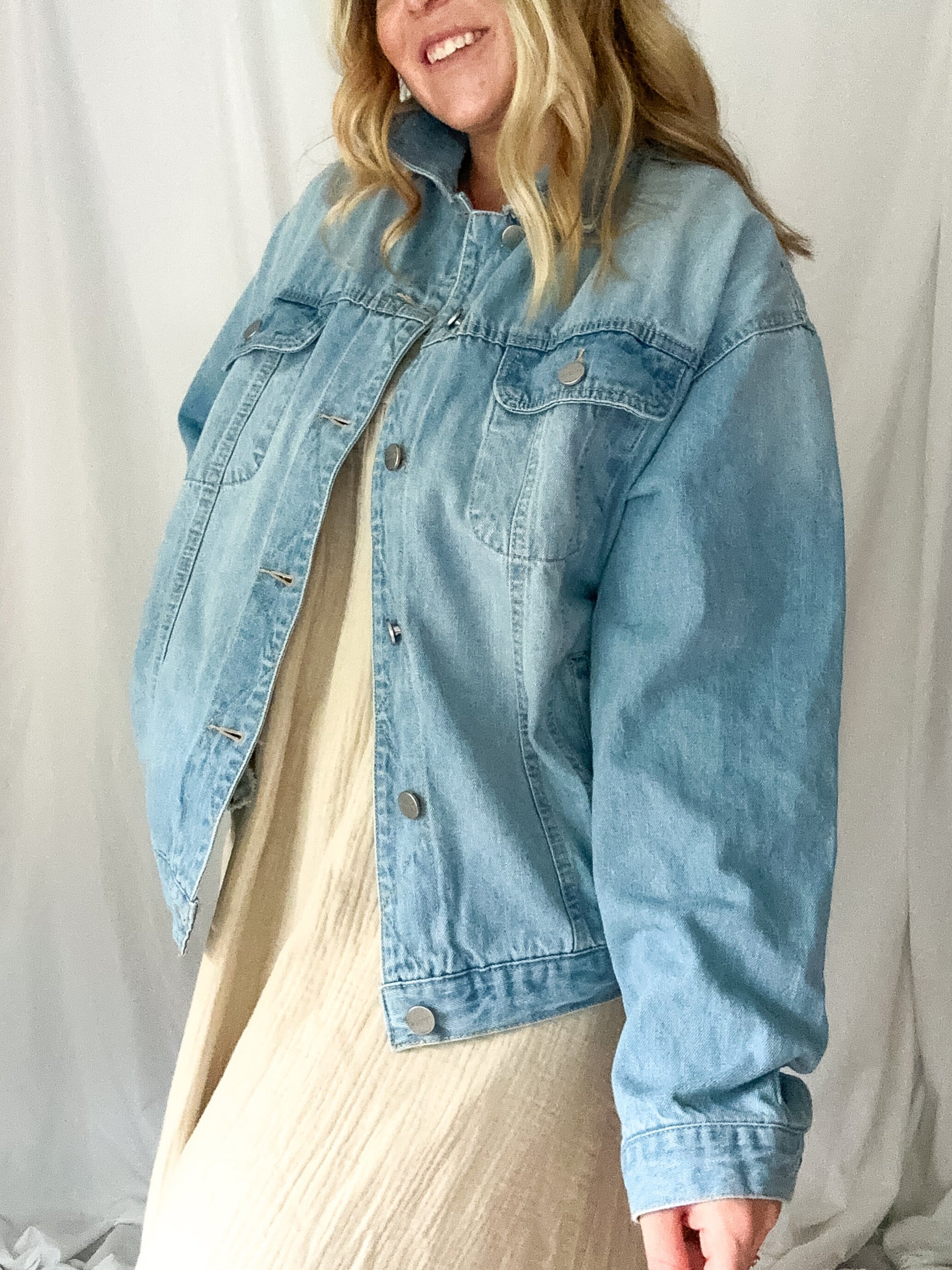 Person wearing a light blue denim jacket against a plain background