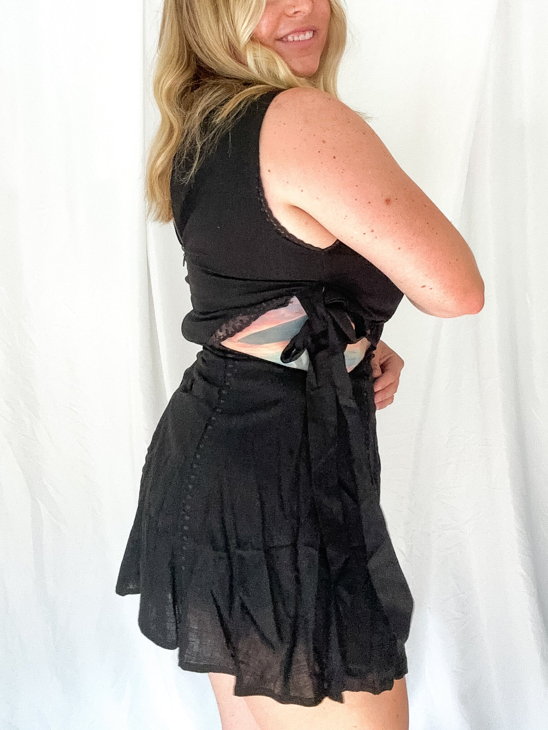 Woman wearing a black sleeveless top and skirt against a white background