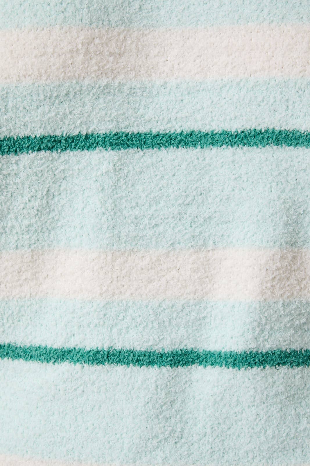 Close-up of a fabric with green and white stripes on a light blue background